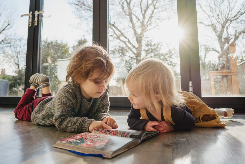 Two children lying on the floor reading together