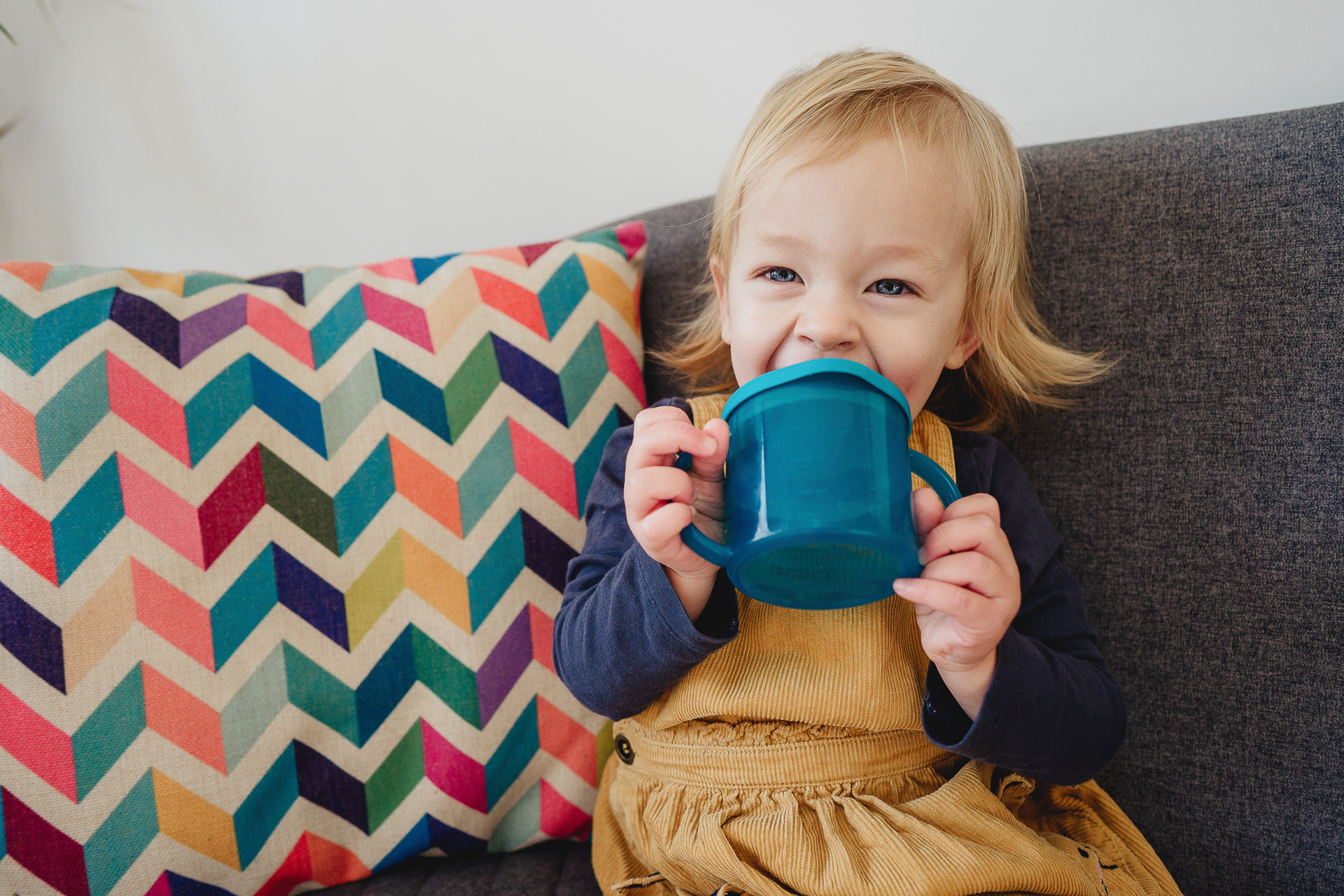 A toddler girl drinking from a blue cup