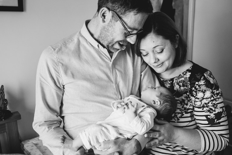 New parents cuddling a newborn baby in their home together