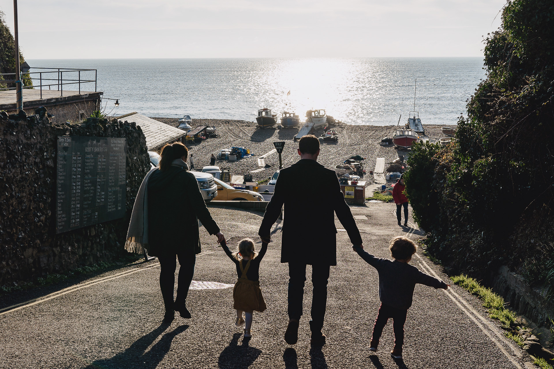 A family of four walking towards the beach holding hands