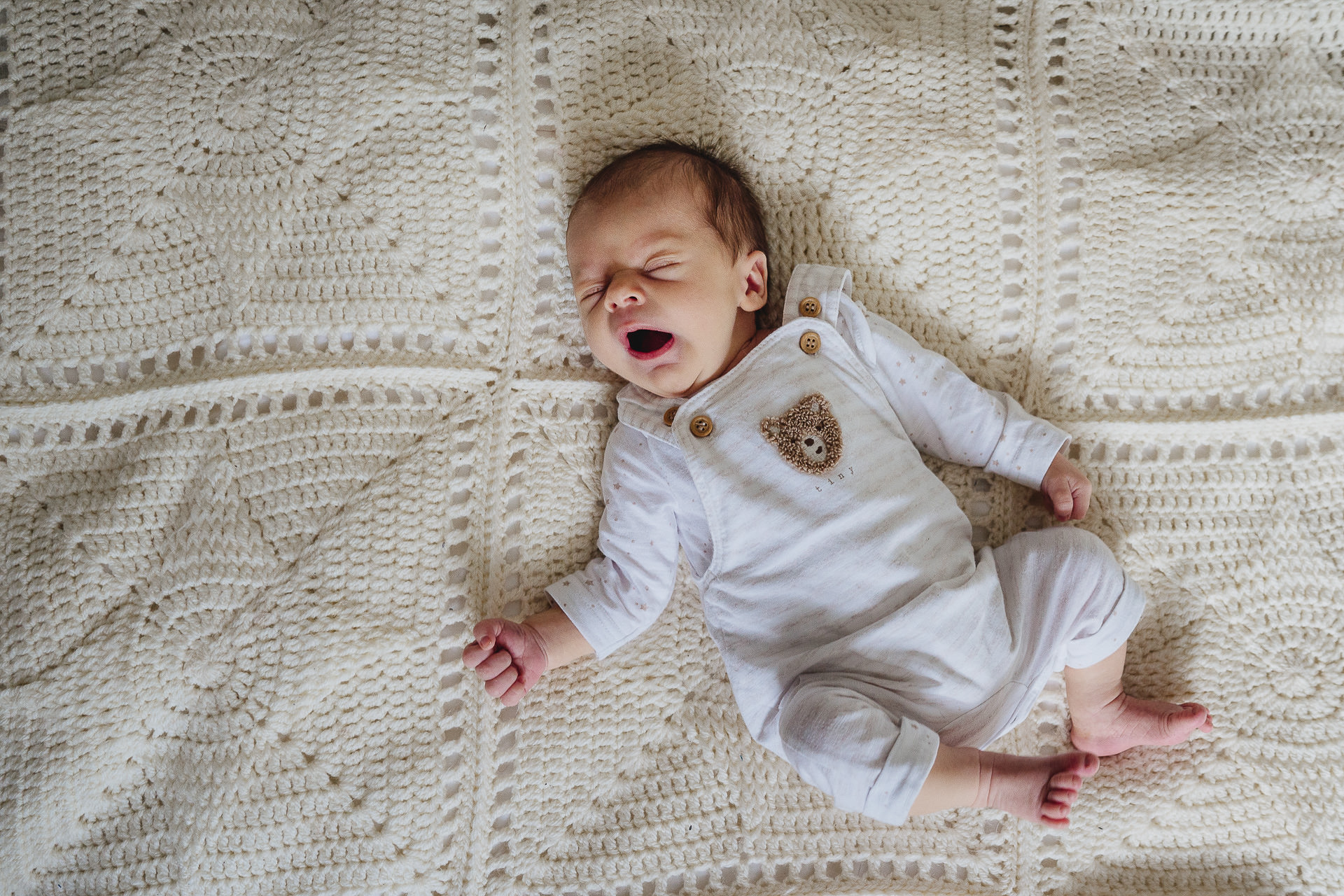 A baby yawning on a blanket