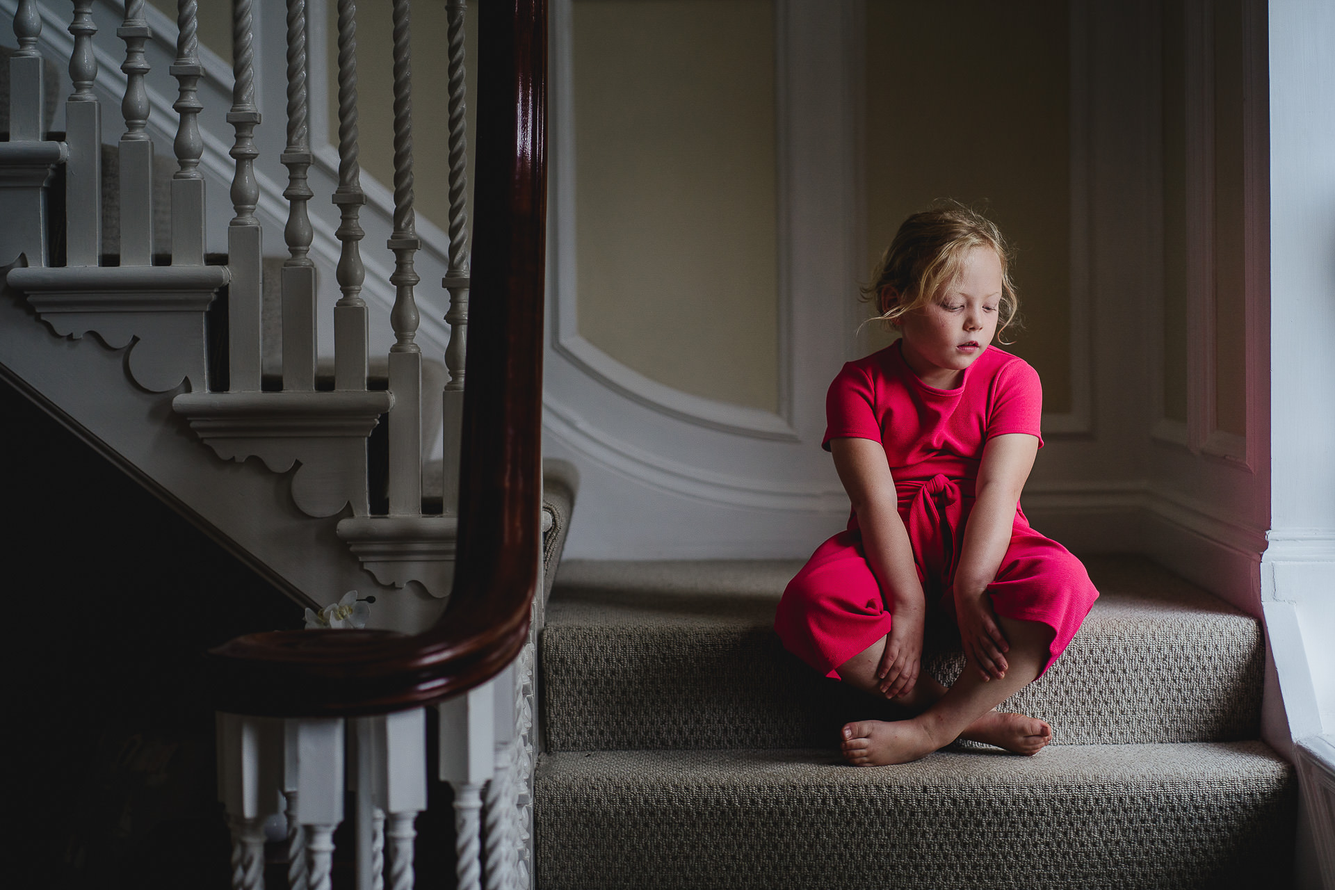 A girl in a pink jumpsuit on a staircase