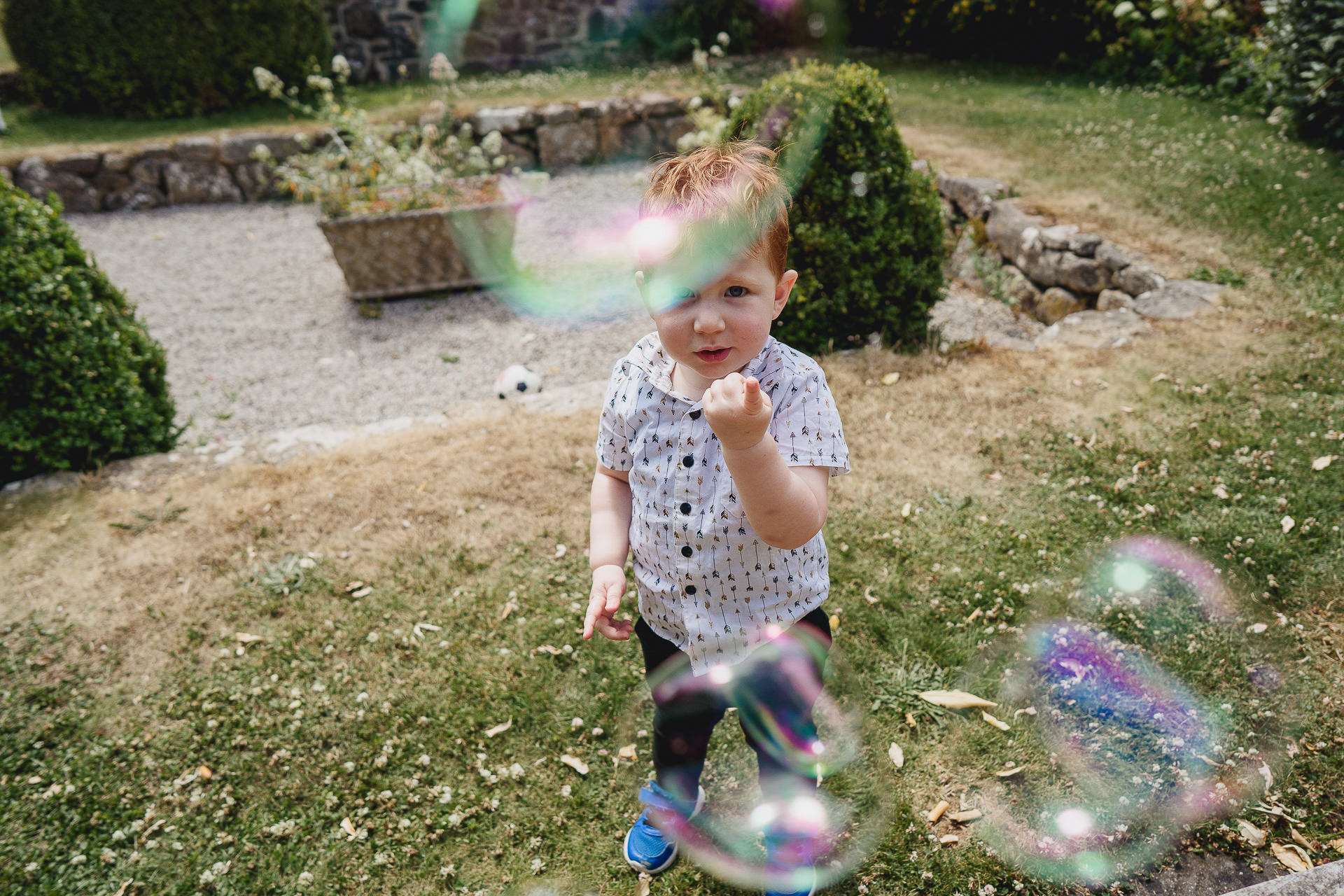 Small boy looking at bubbles in a garden