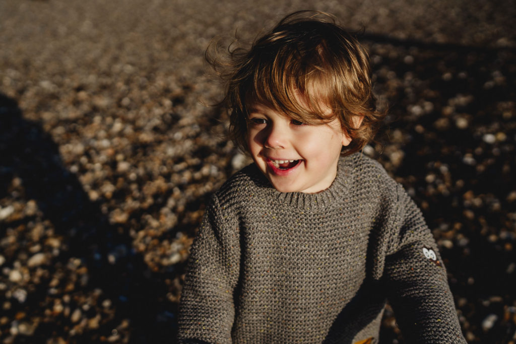 A young boy in a grey jumper laughing