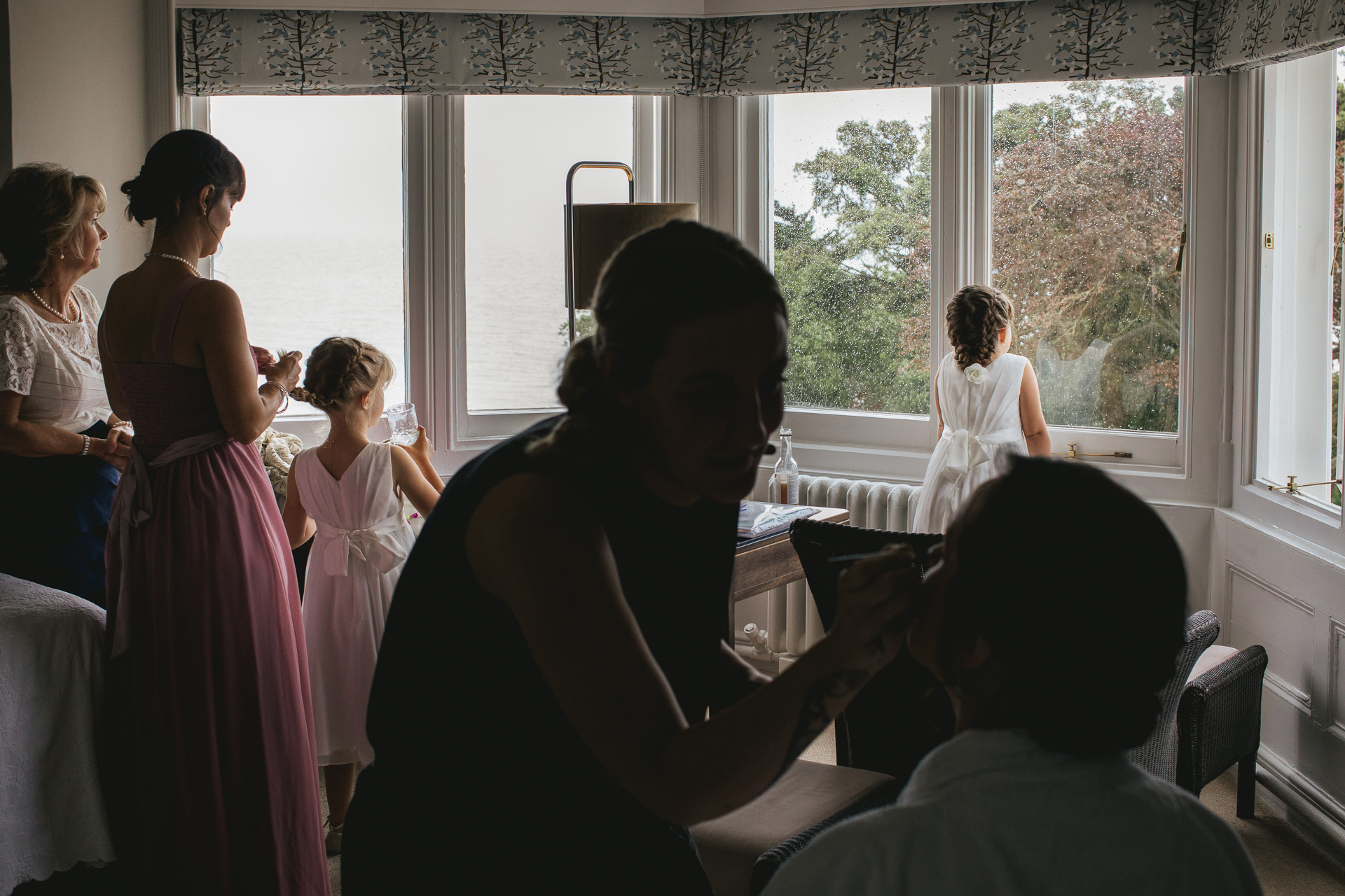 Bride and flower girls getting ready for wedding, watching the rain outside