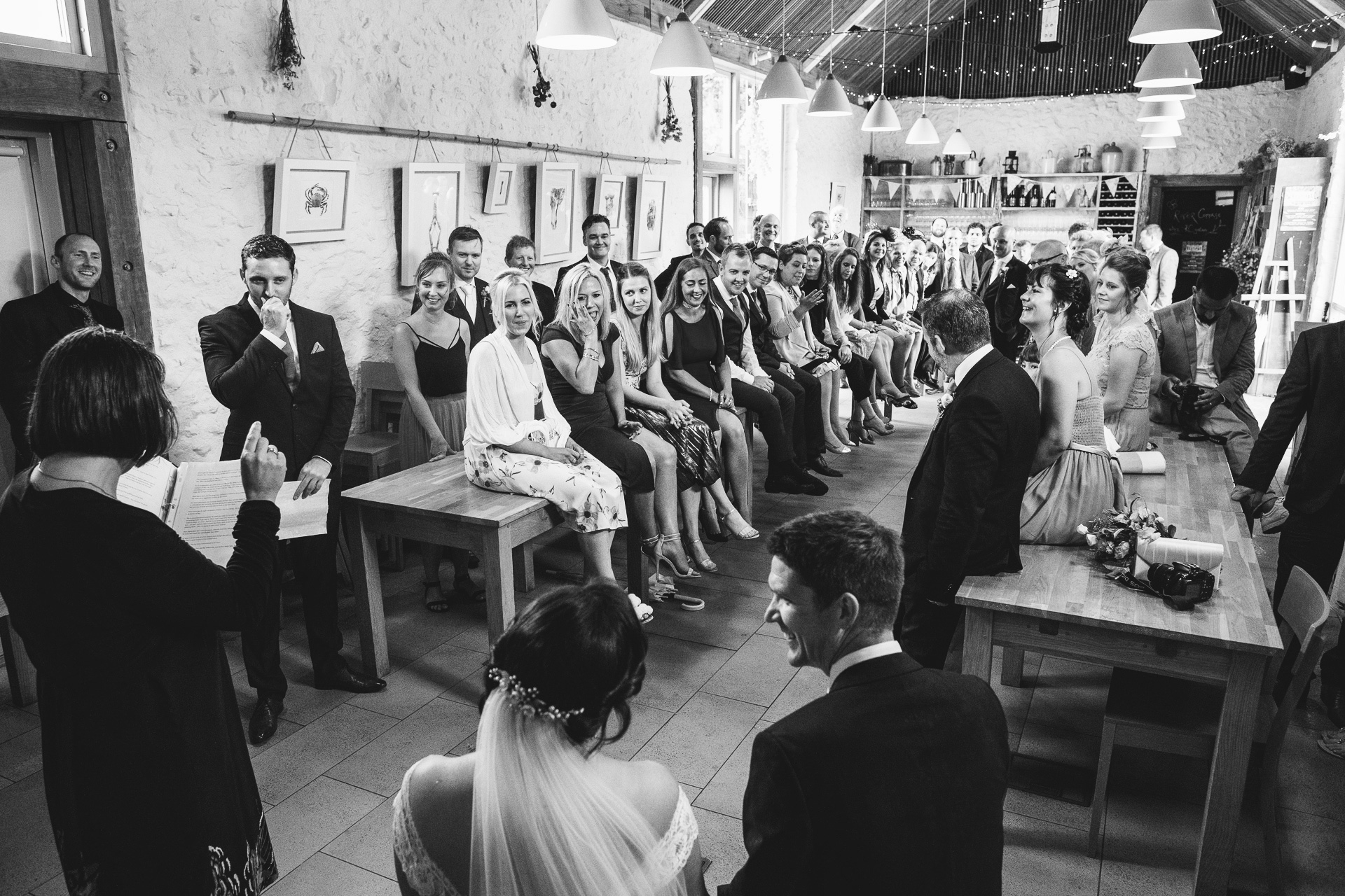 A wedding ceremony with guests sitting on long tables