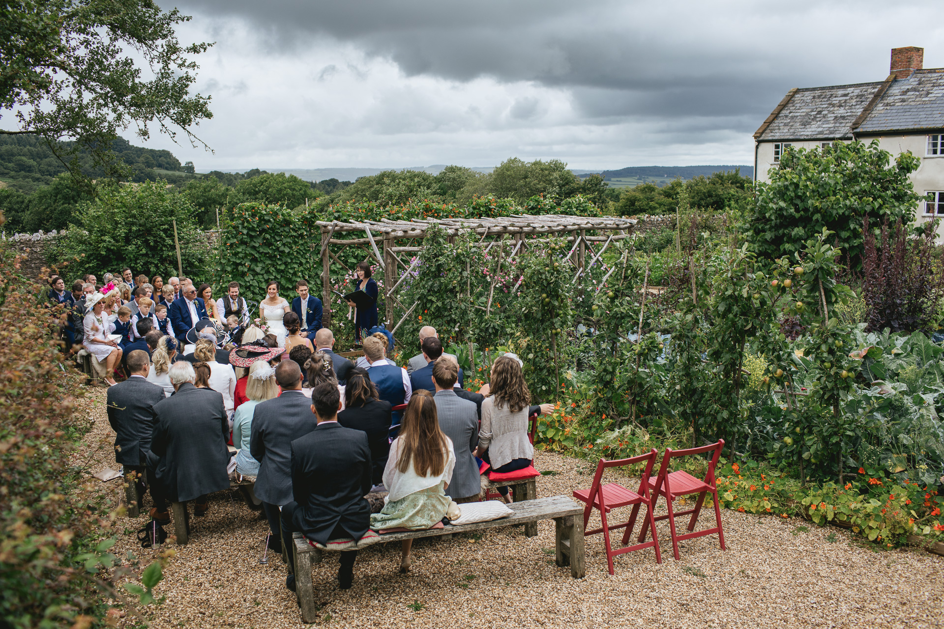 An outdoor humanist ceremony in the kitchen garden with rain clouds in the sky. 
