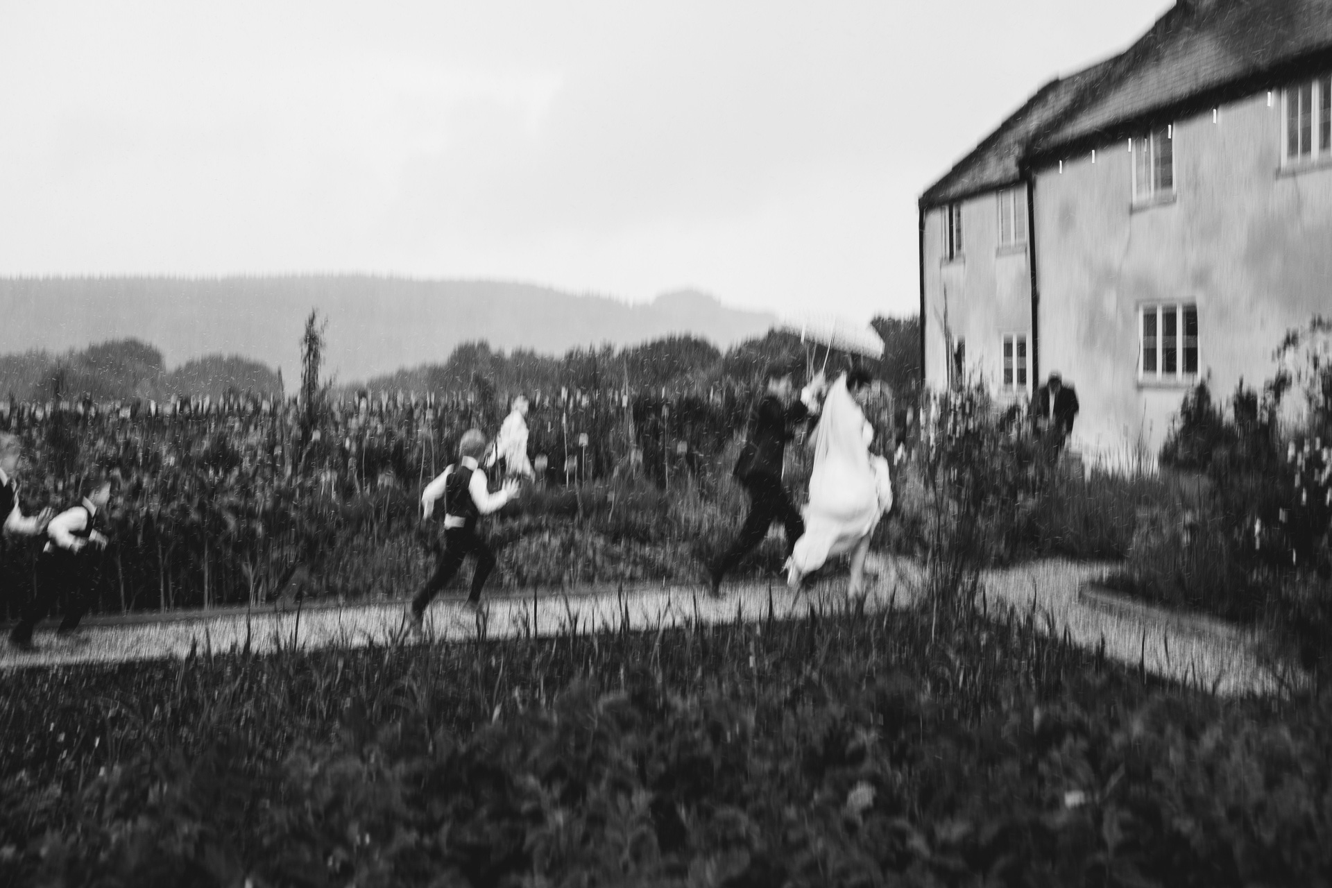 Bride and groom running for shelter in the pouring rain at a wet weather wedding ceremony