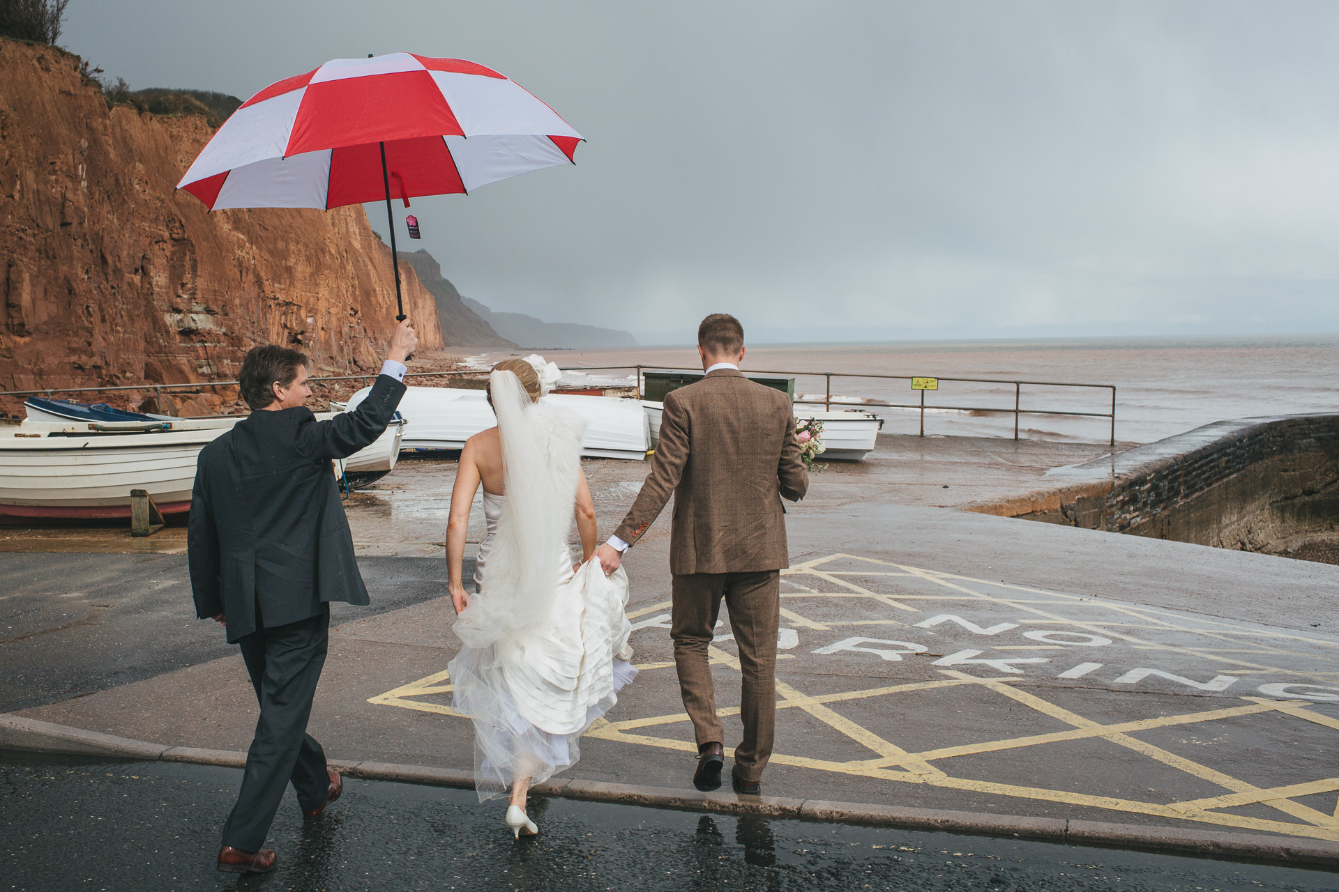 A bride and groom by a stormy sea front at Sidmouth