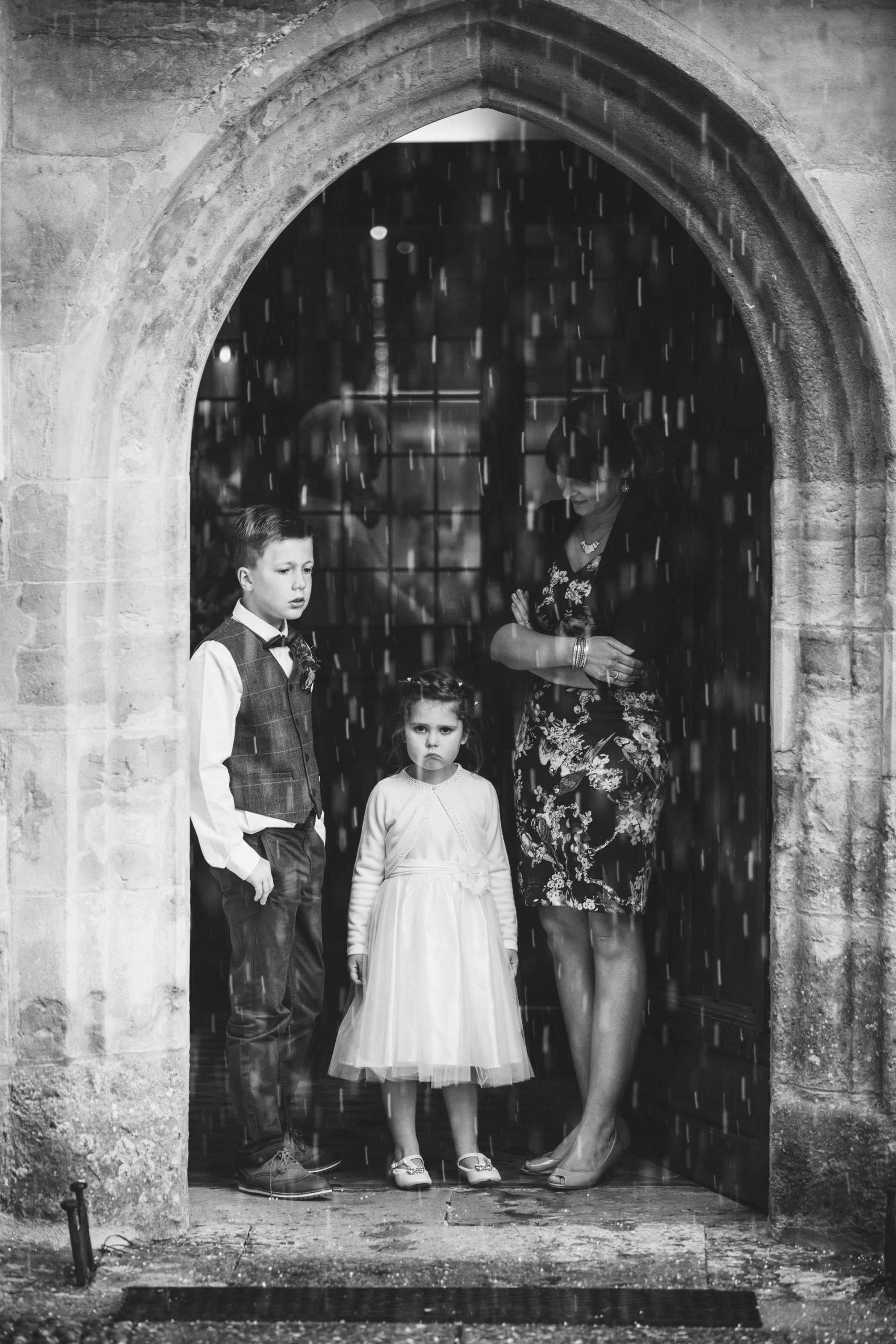 A flower girl frowning at the rain on a wet weather wedding day.