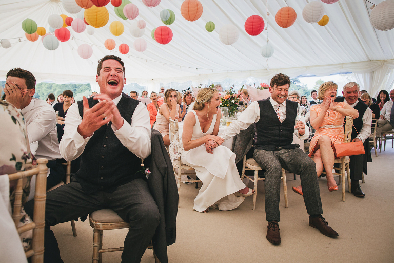 Wedding guests laughing in a marquee decorated with colourful lanterns