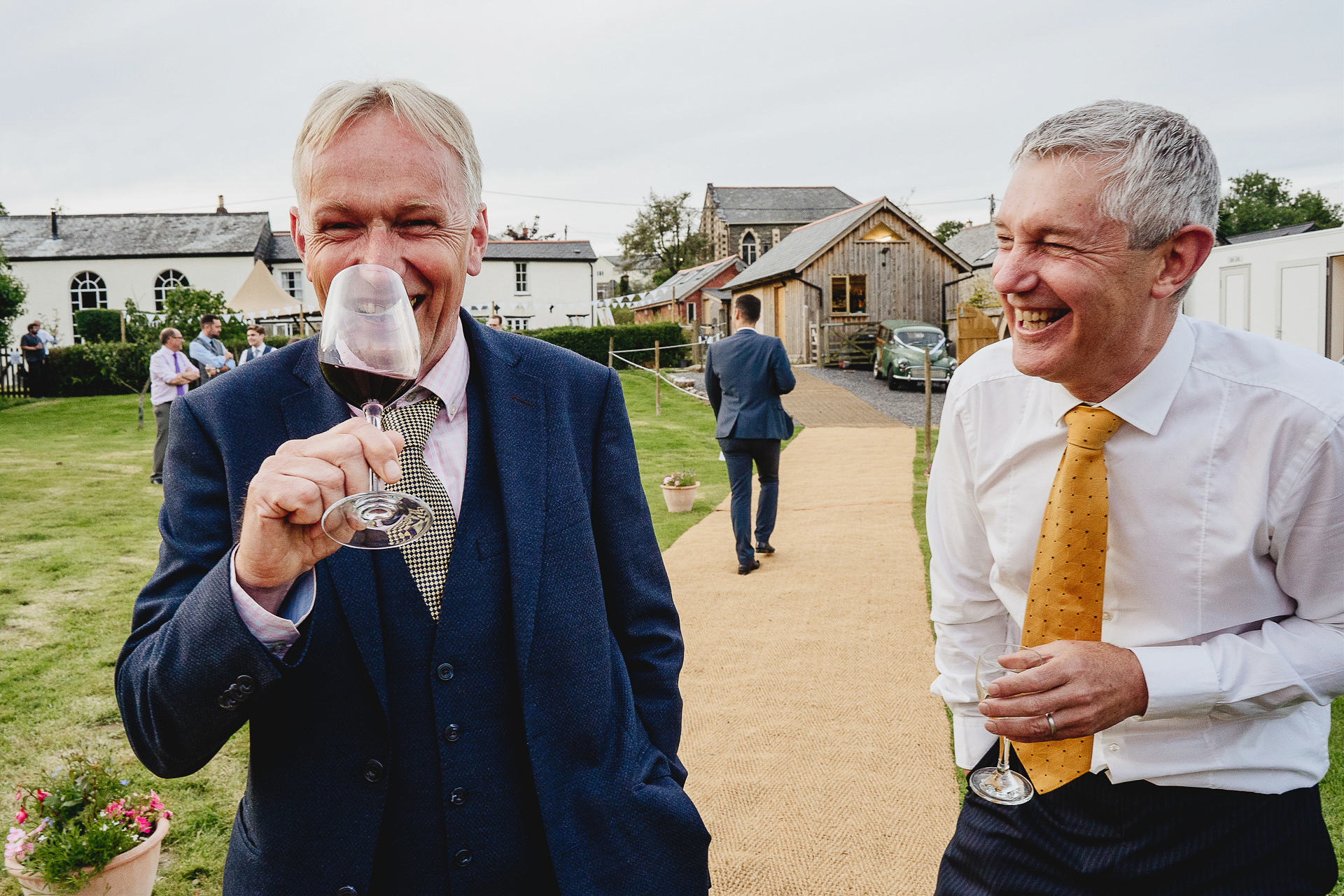 Two men drinking wine and laughing in a field together