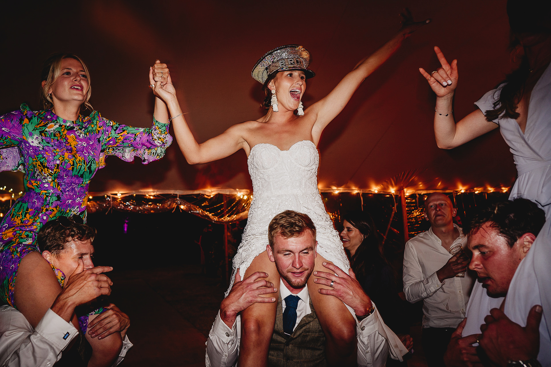 Bride and wedding guests dancing on men's shoulders