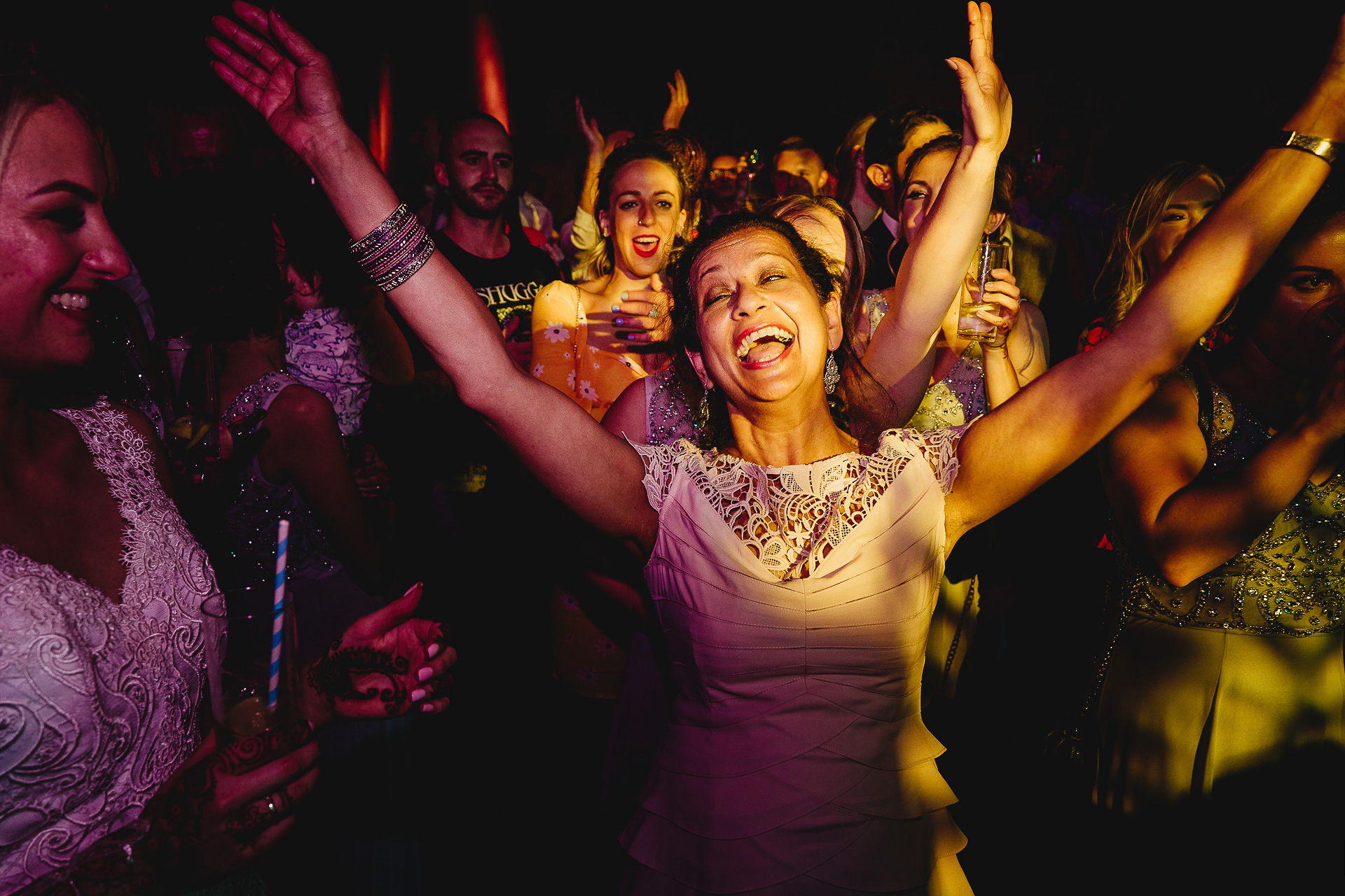 Mother of the groom throwing her arms in the air on the dancefloor
