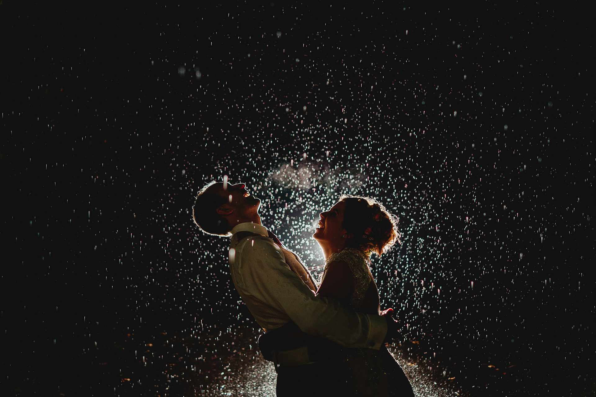 Bride and groom laughing in the rain together at night