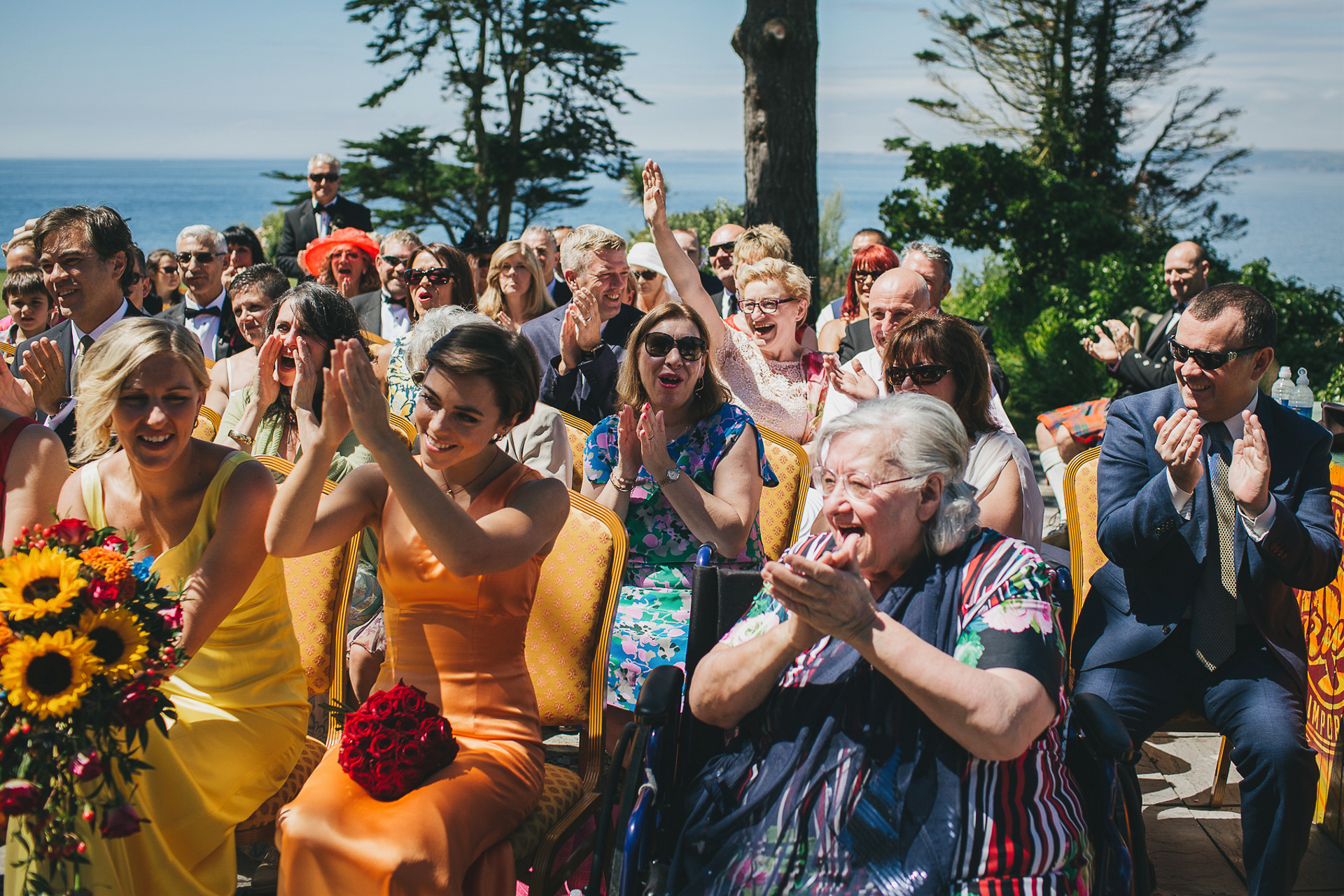 Wedding guests clapping and cheering with the sea behind