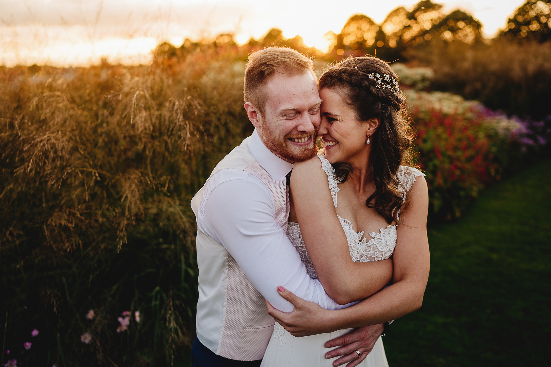Overjoyed bride and groom cuddling in a sunset