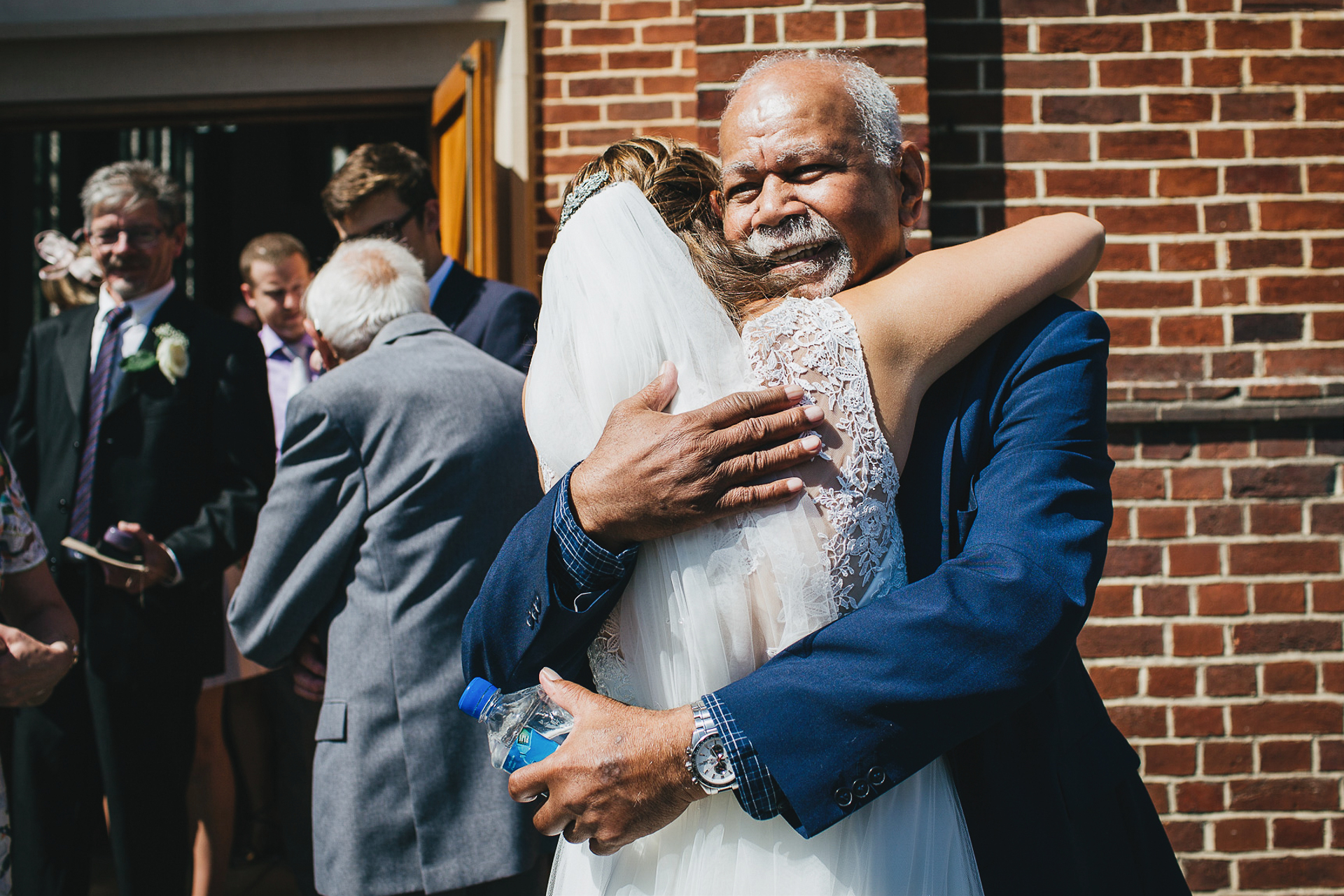 Grandfather hugging bride outside church