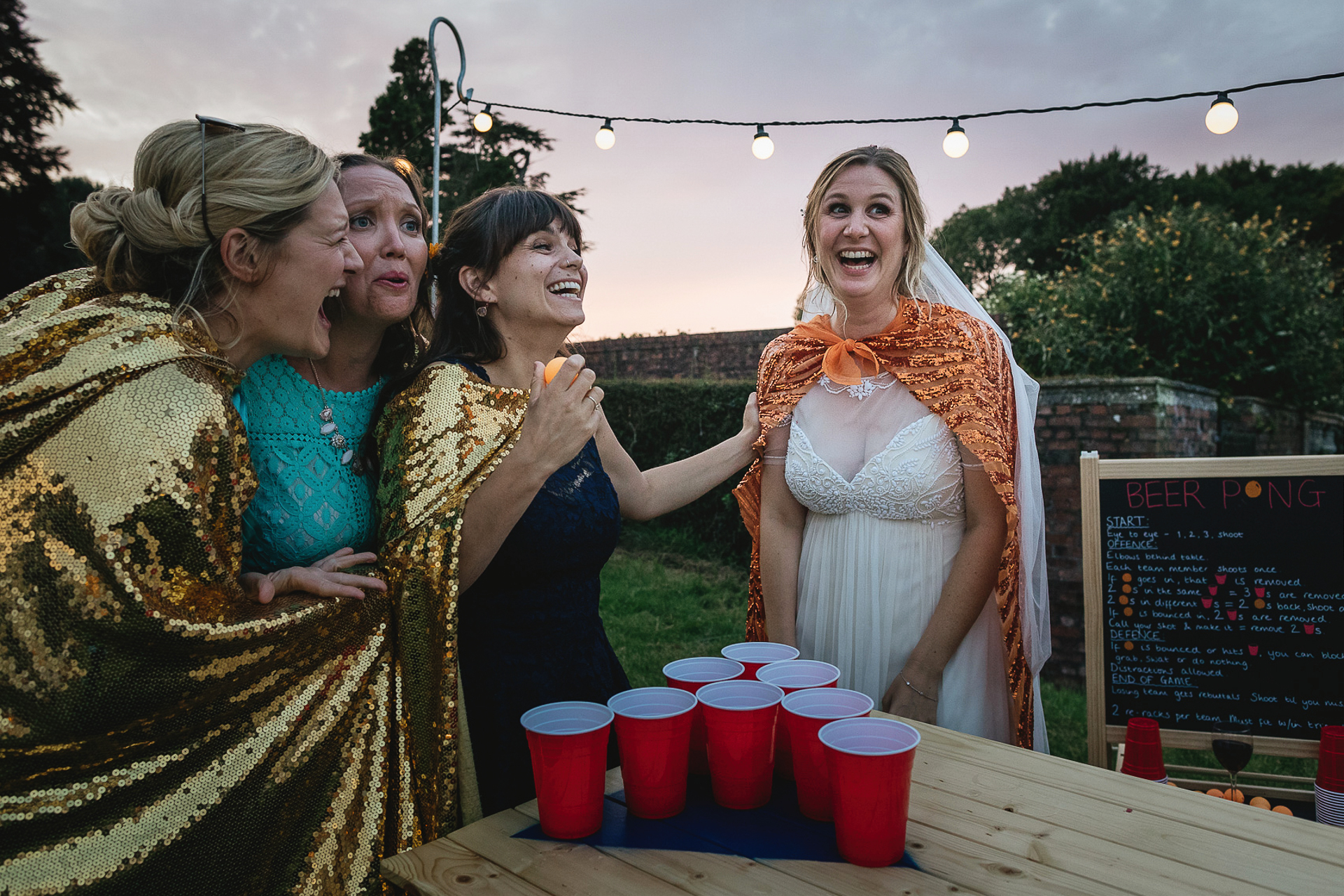 Bride laughing with friends playing beer pong