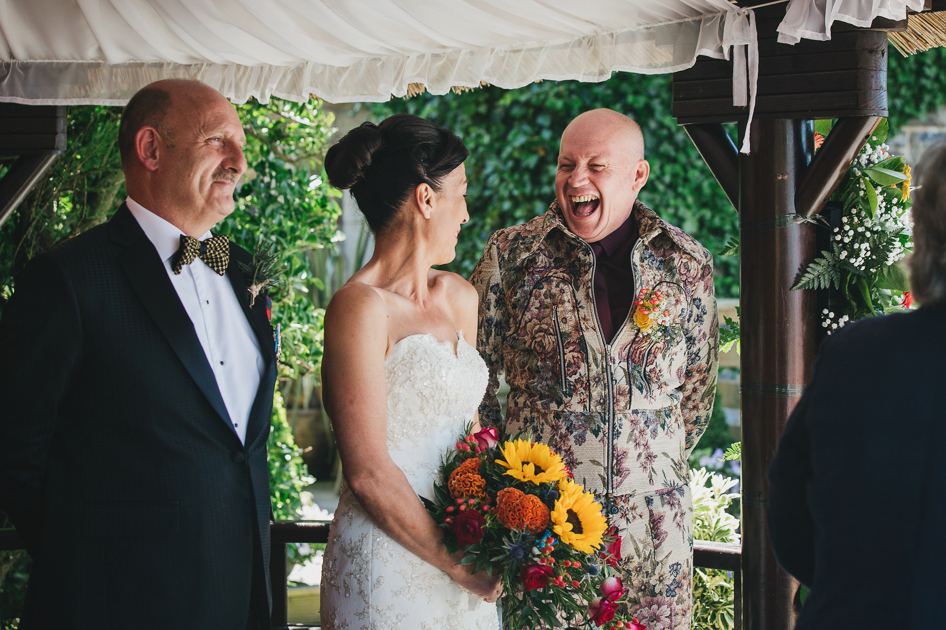 Man in floral suit smiling widely at bride