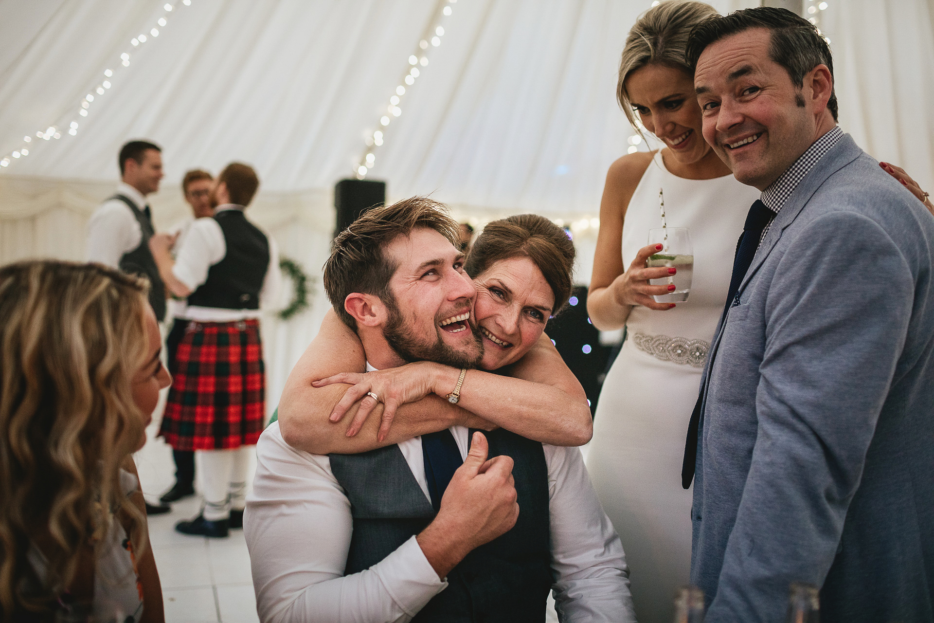 Wedding guests smiling and cuddling in a marquee