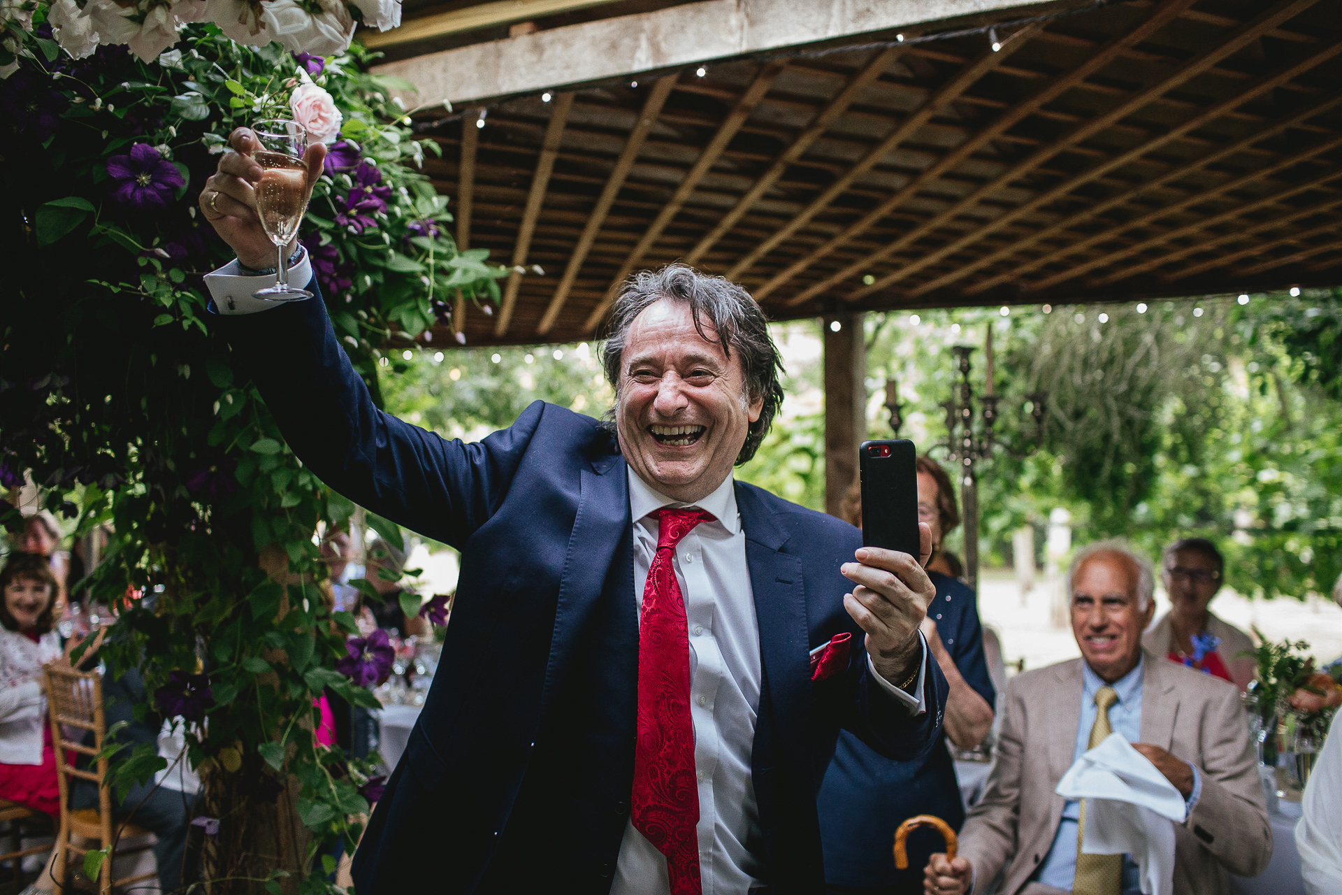 Wedding guest grinning broadly and waving champagne