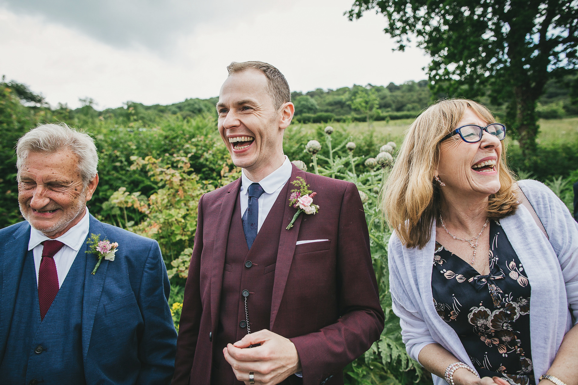 Groom and parents laughing in a garden