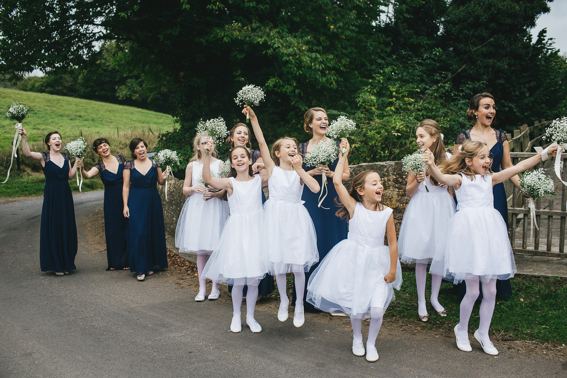 Group of bridesmaids and flower girls waving excitedly