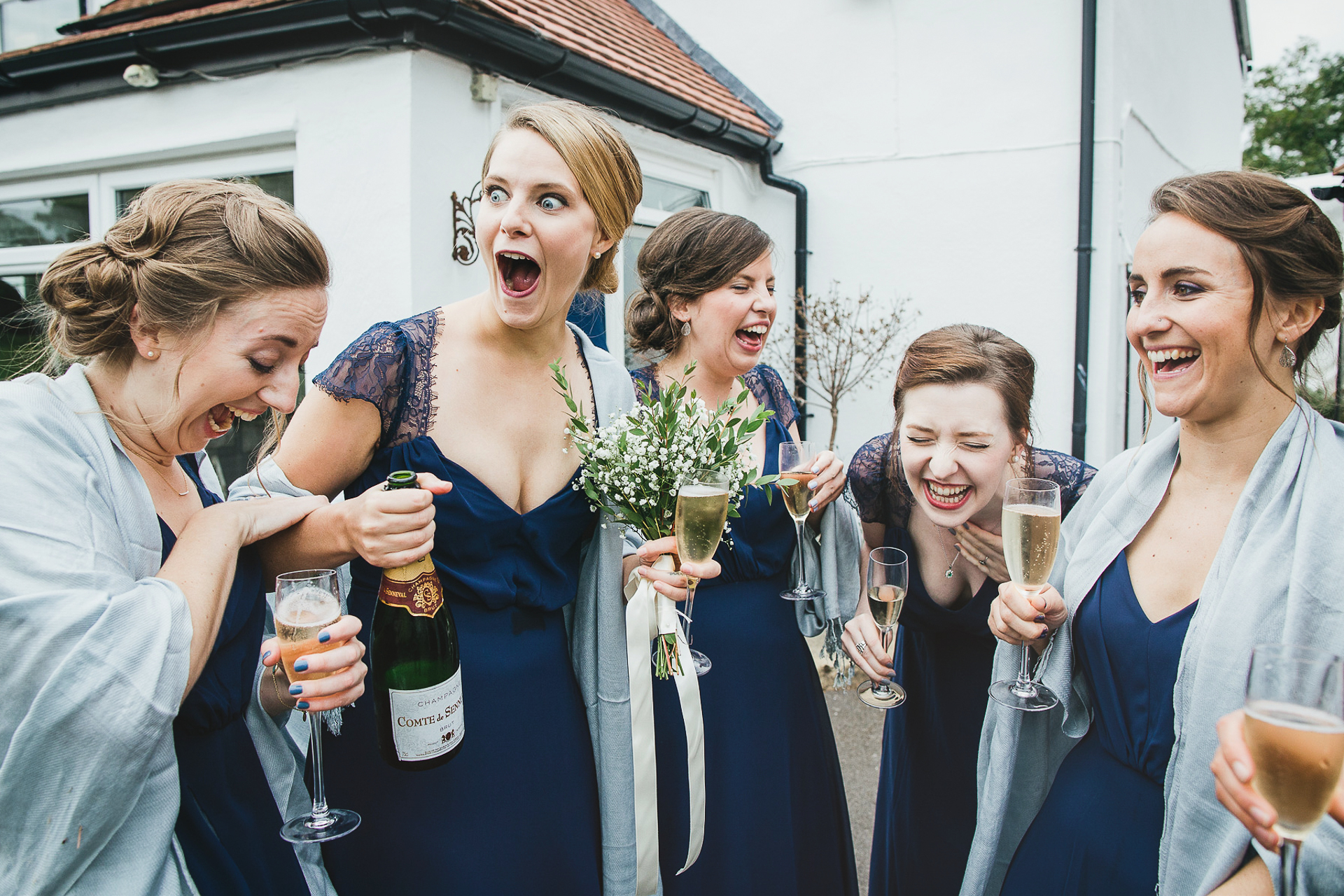 Group of bridesmaids laughing together with champagne