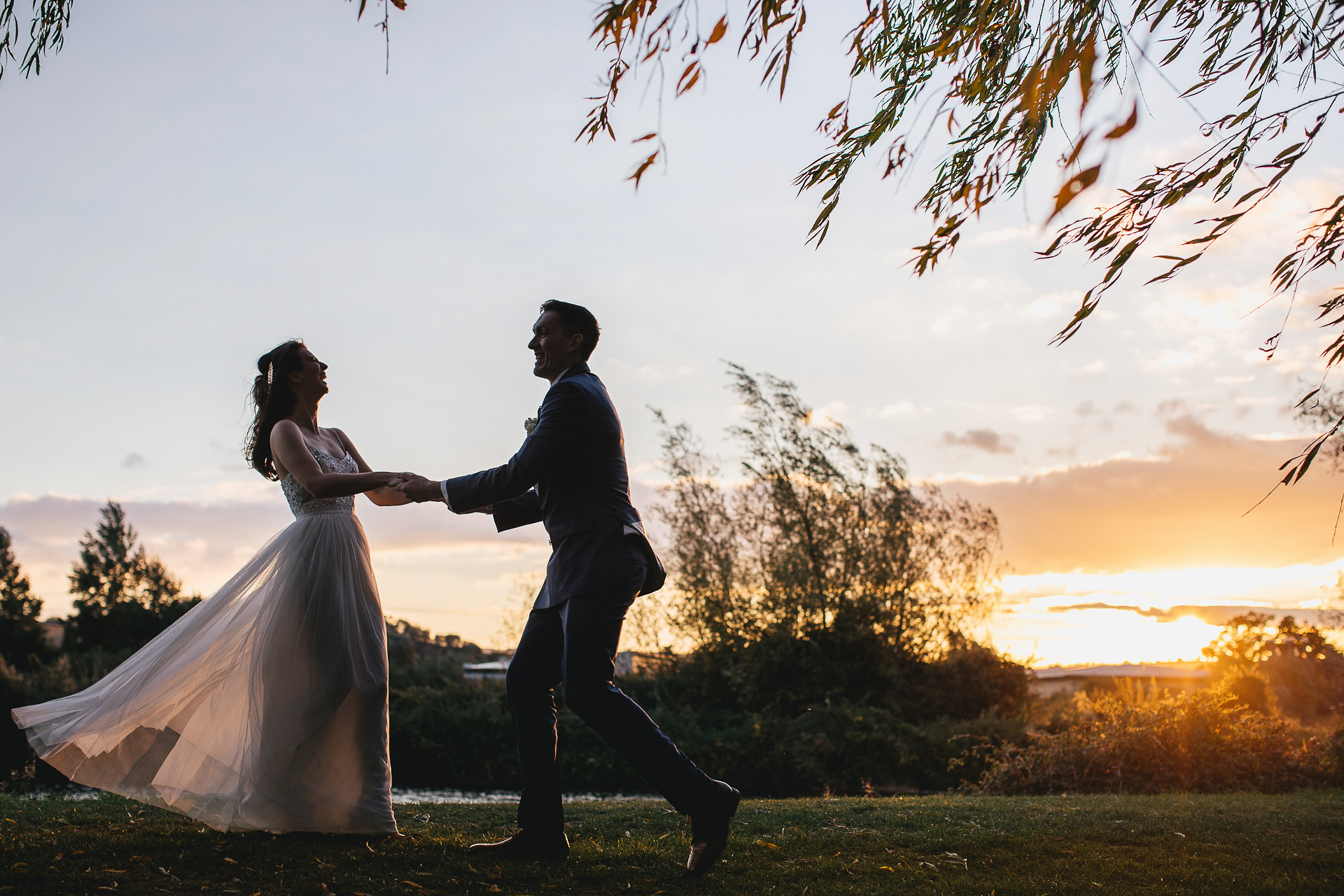 Bride and groom twirling joyfully around in a sunset