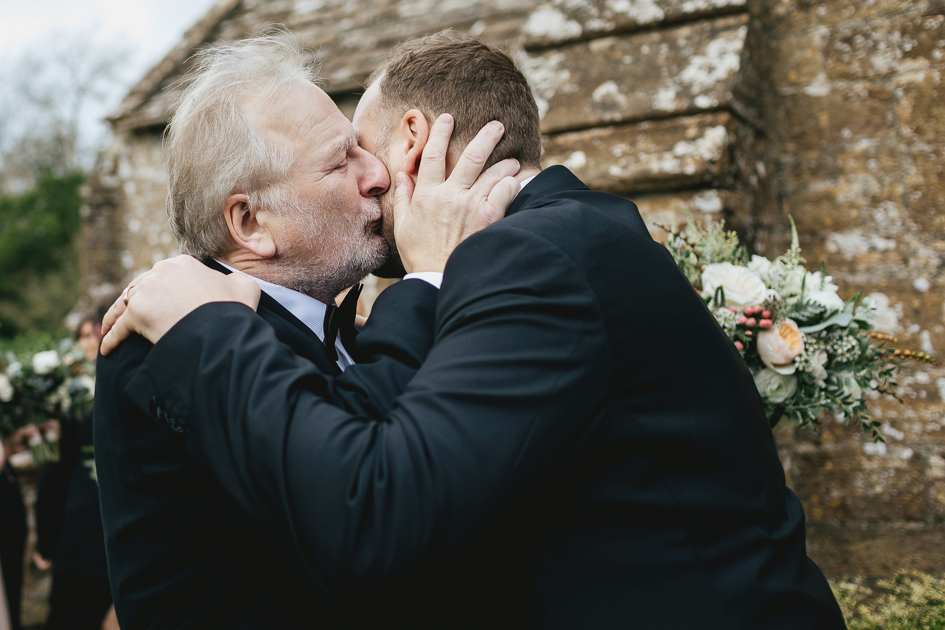 Father kissing groom outside church