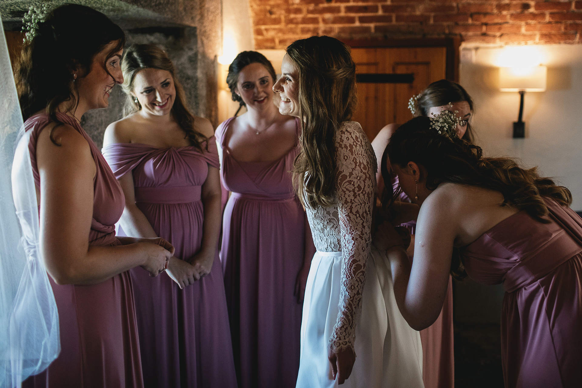 Bride smiling at bridesmaids whilst getting ready for wedding