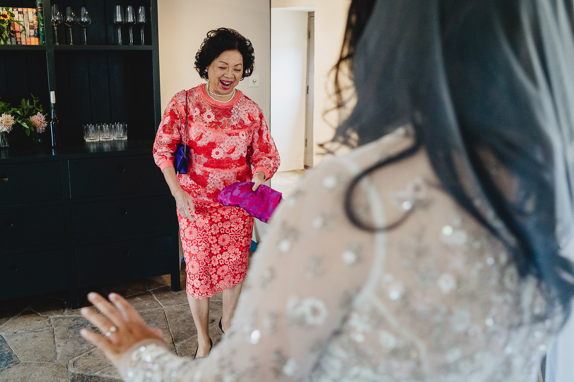 Mother of the bride smiling joyfully at bride in dress