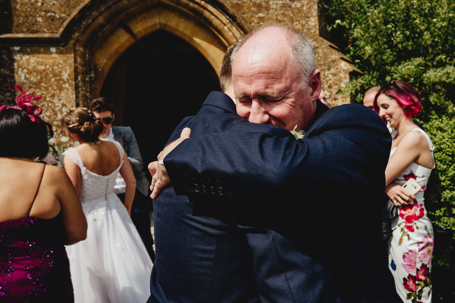 Father hugging groom outside church
