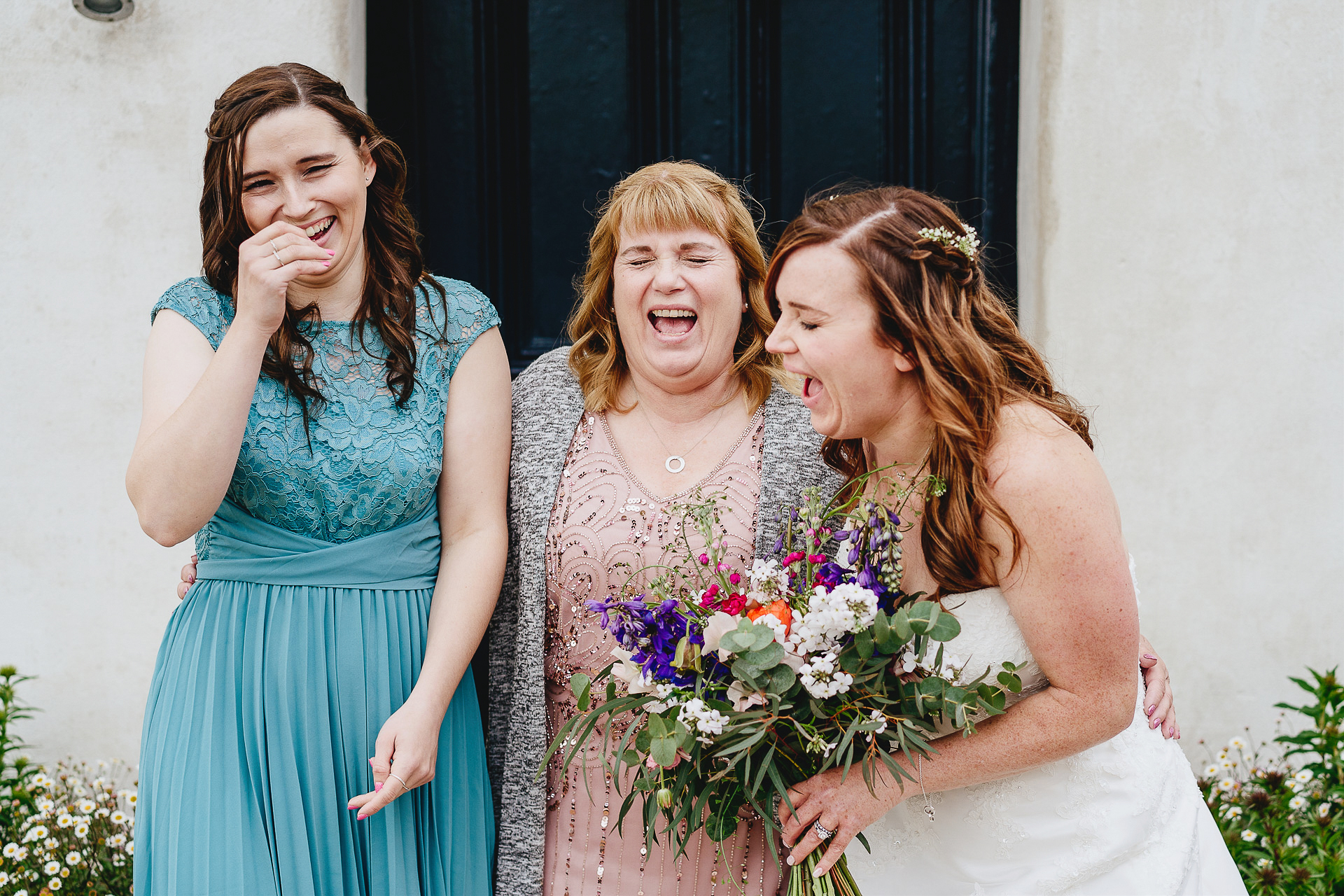 Bride laughing with mother and sister