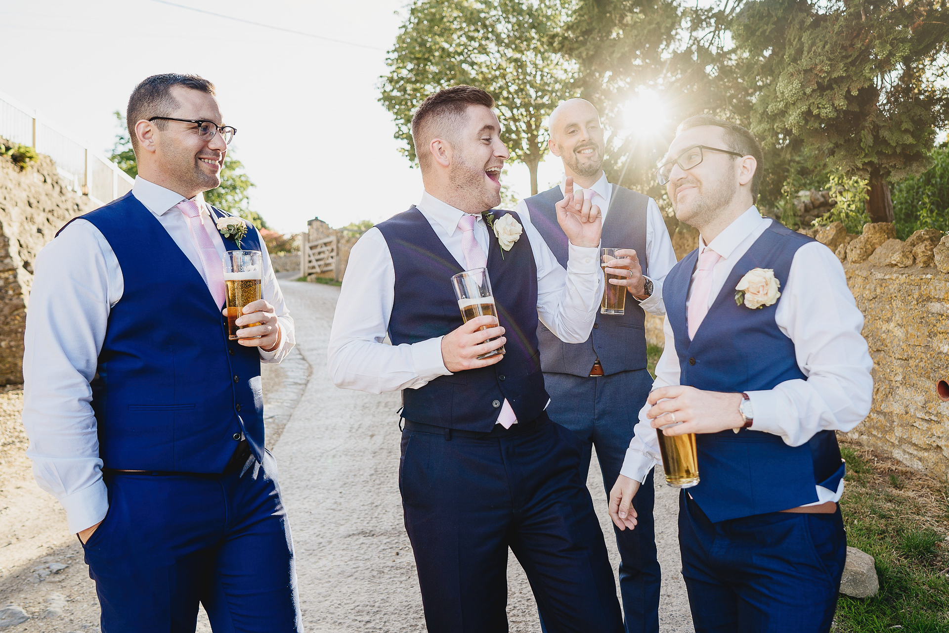 Groom and groomsmen laughing and drinking together