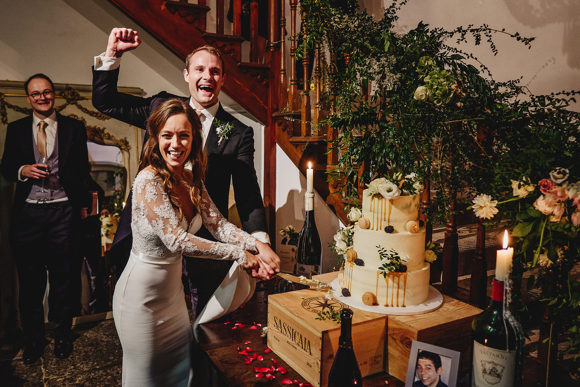 Bride and groom cheering and smiling while cutting cake