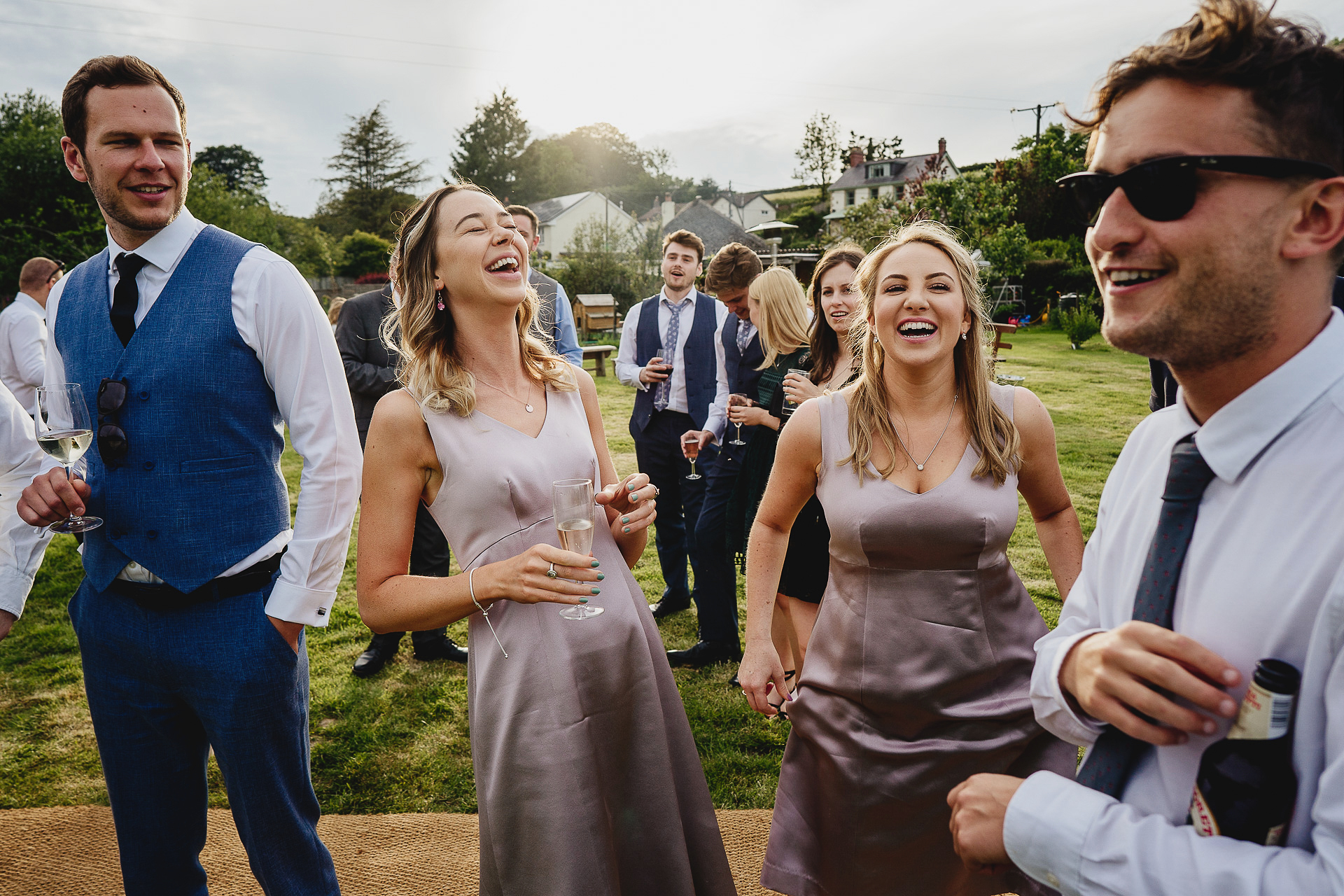 Bridesmaids and wedding guests laughing in a field