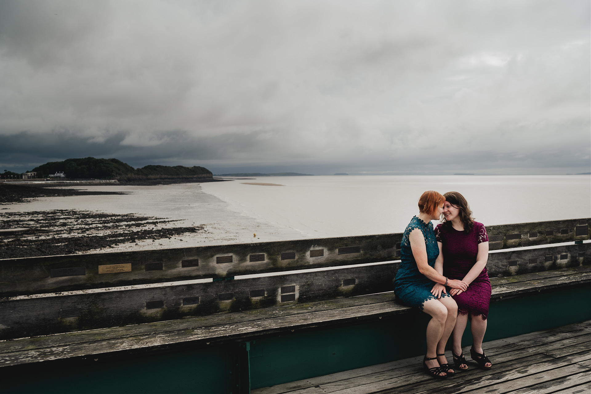 Bride and bride on Clevedon pier with dark clouds in skies above