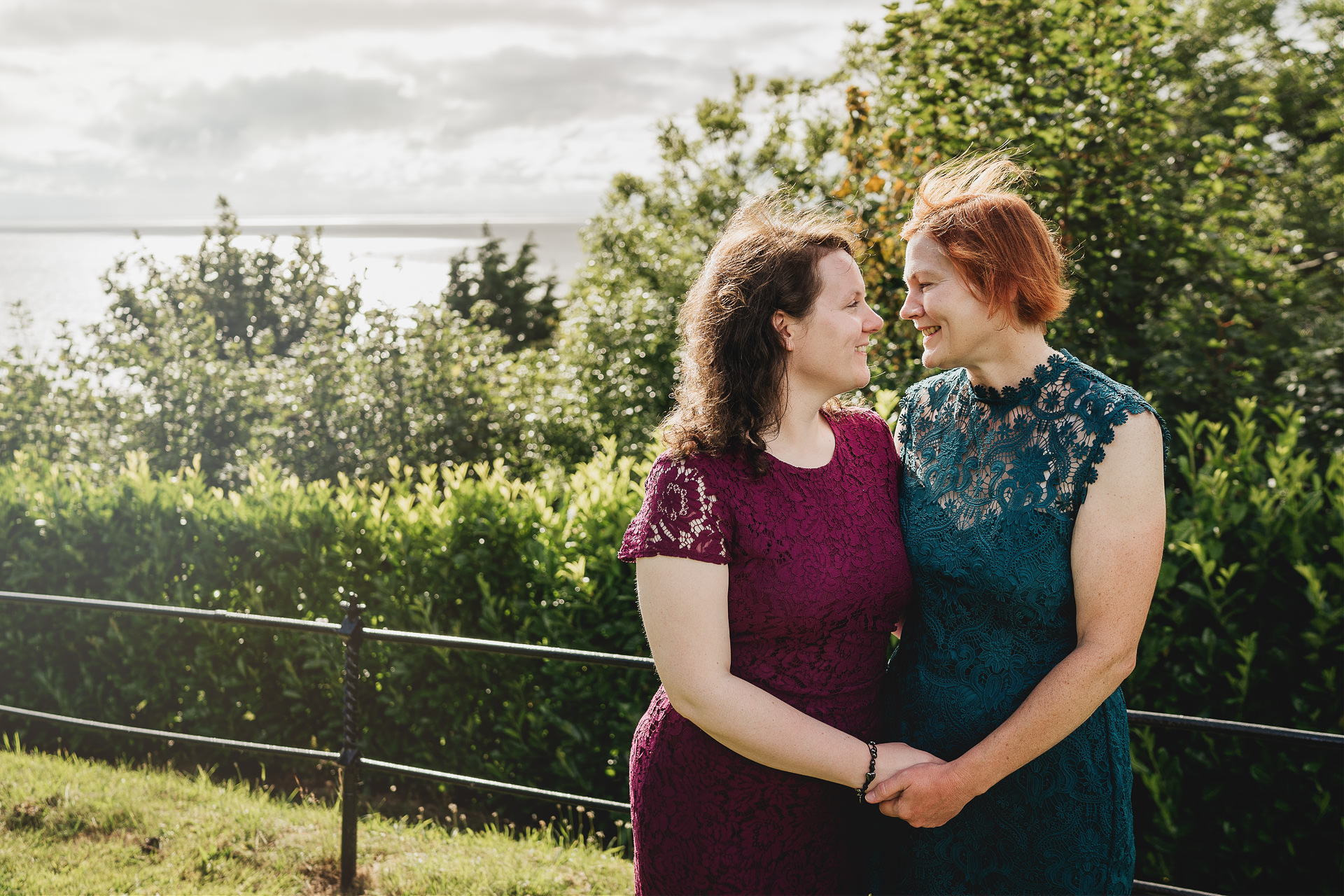 Two brides in colourful dresses smiling at each other