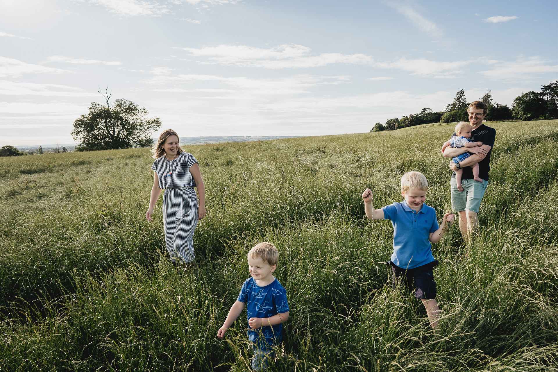 A family walking together through long grass in evening sunlight