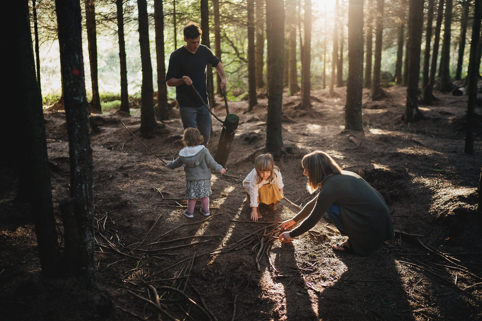 A family in the woods in evening light, gathering sticks