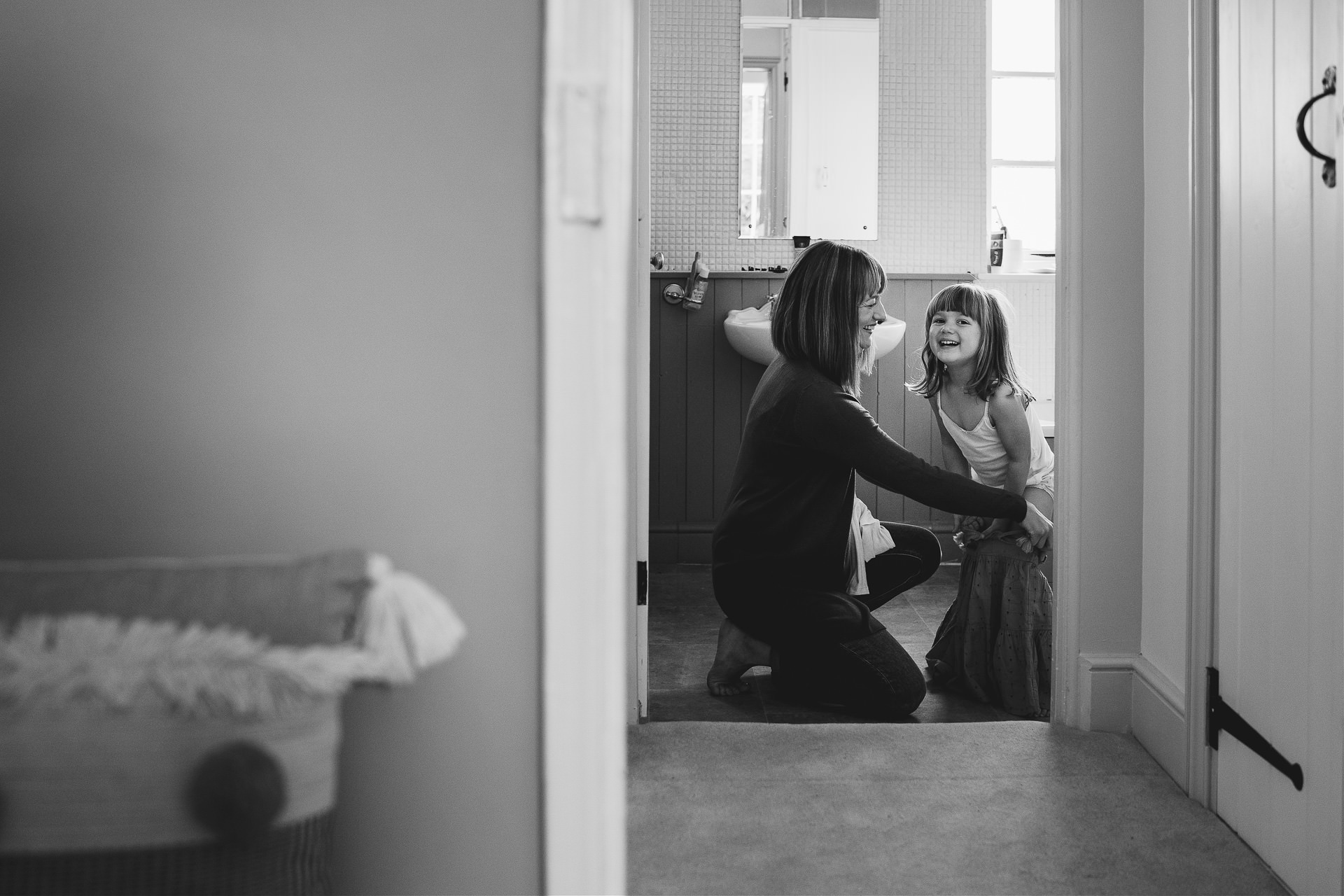 A young girl and her mother smiling and getting ready in a bathroom