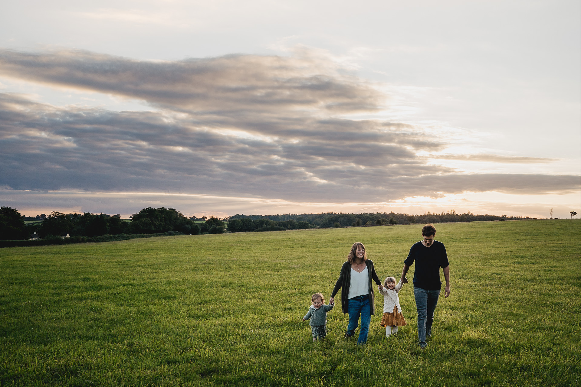 A family walking together across a field as the sun sets