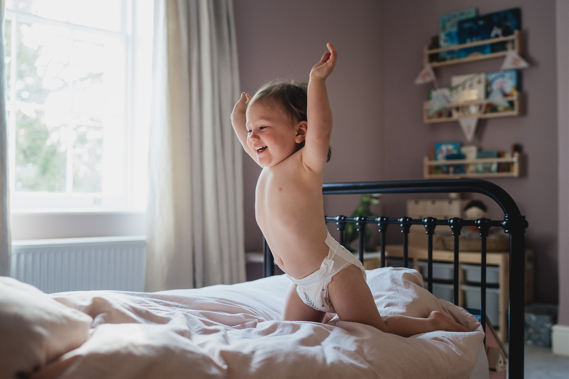 A toddler leaping onto a bed