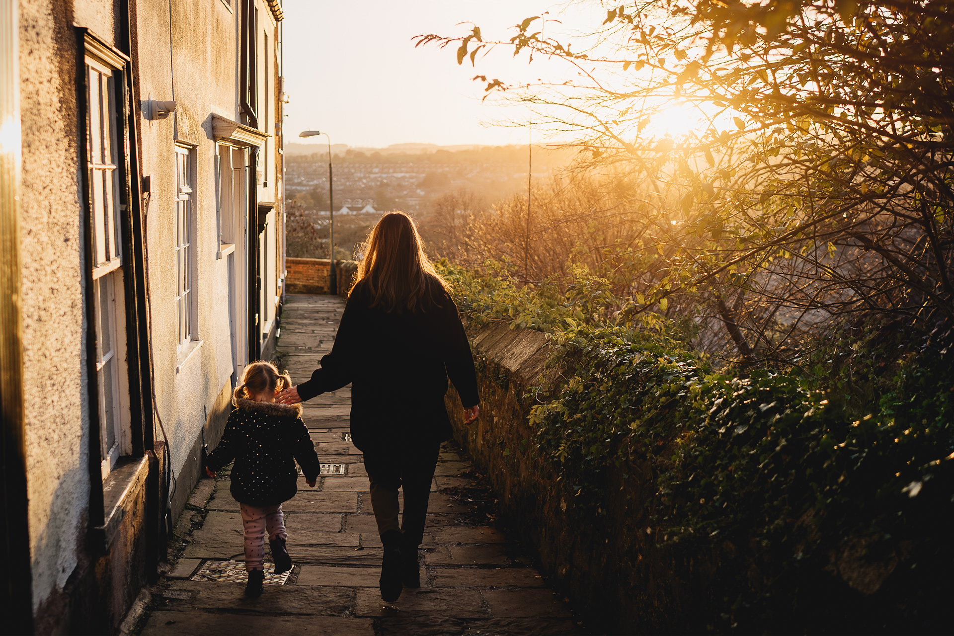 Exeter family photography of two sisters walking together in evening light