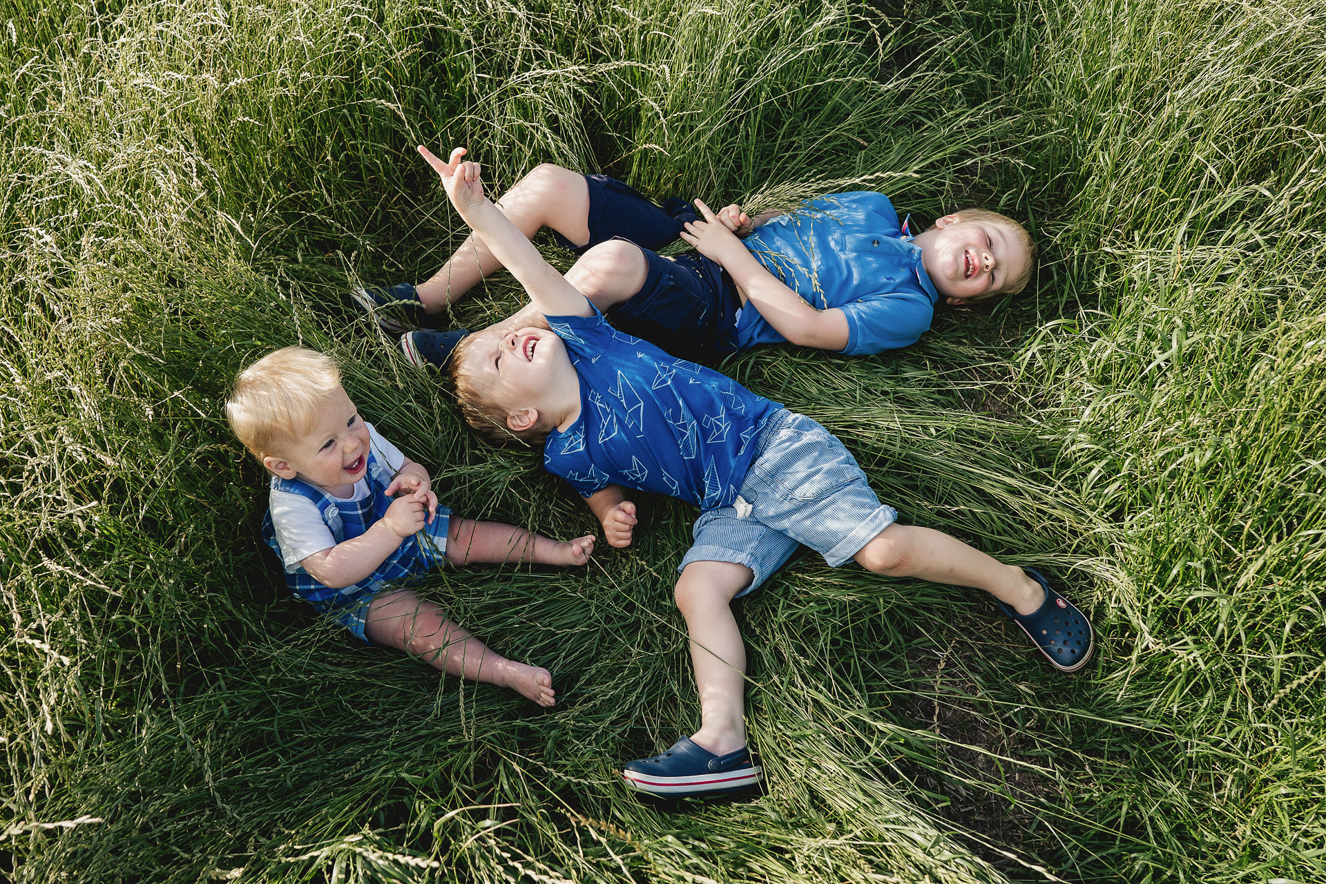 Three young brothers lying in long grass