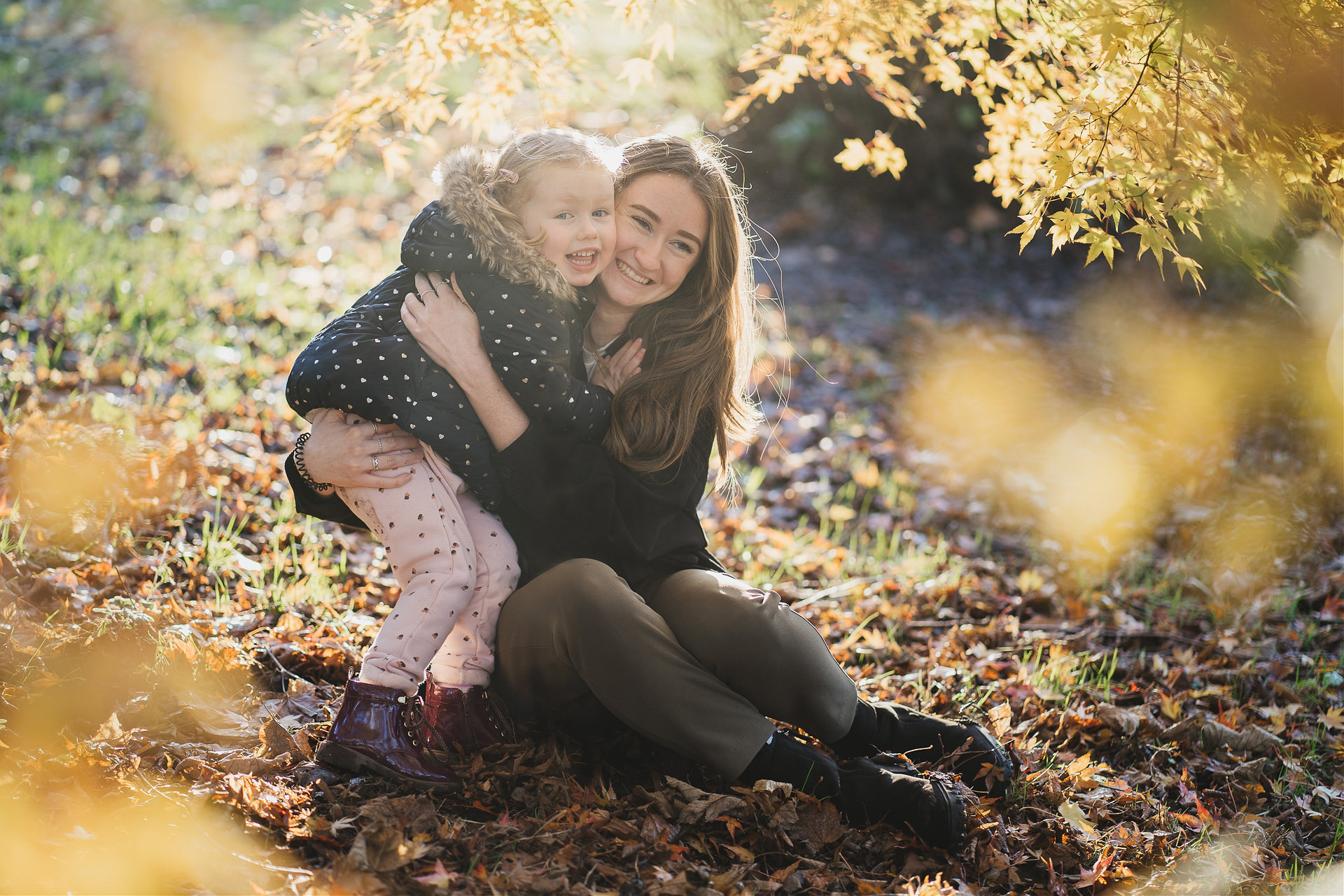 Exeter family photography of two sisters cuddling together in autumn leaves