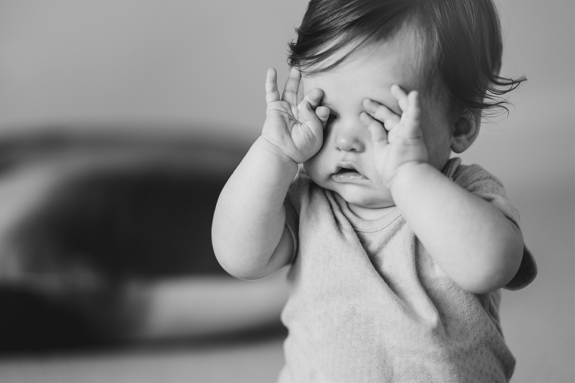 Black & white image of a baby rubbing her eyes