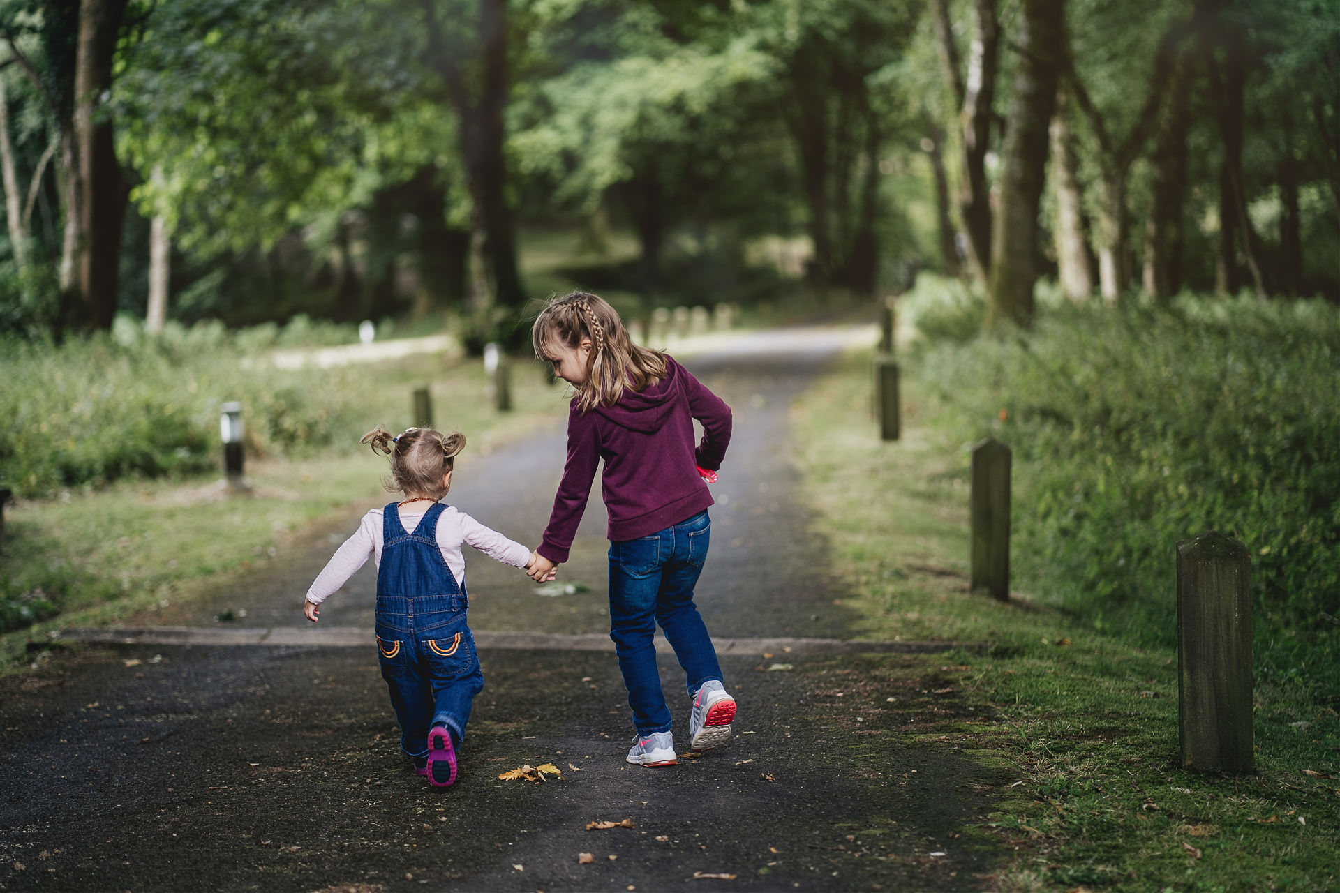 Two sisters walking hand in hand down a woodland path